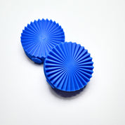Two blue silicone fan presses with a round, pleated geometric design.