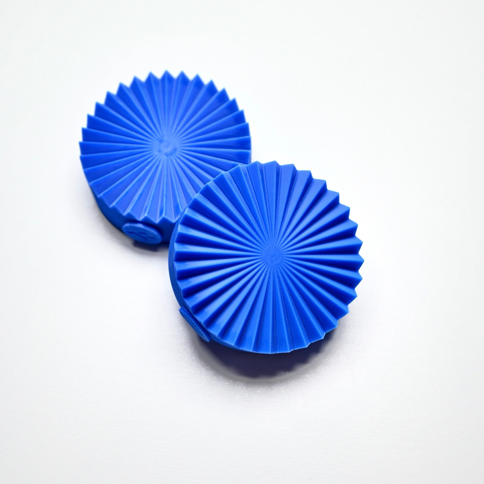 Two blue silicone fan presses with a round, pleated geometric design.