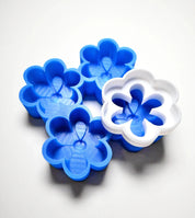 Blue silicone daisy molds with a white flower-shaped cutter on top.