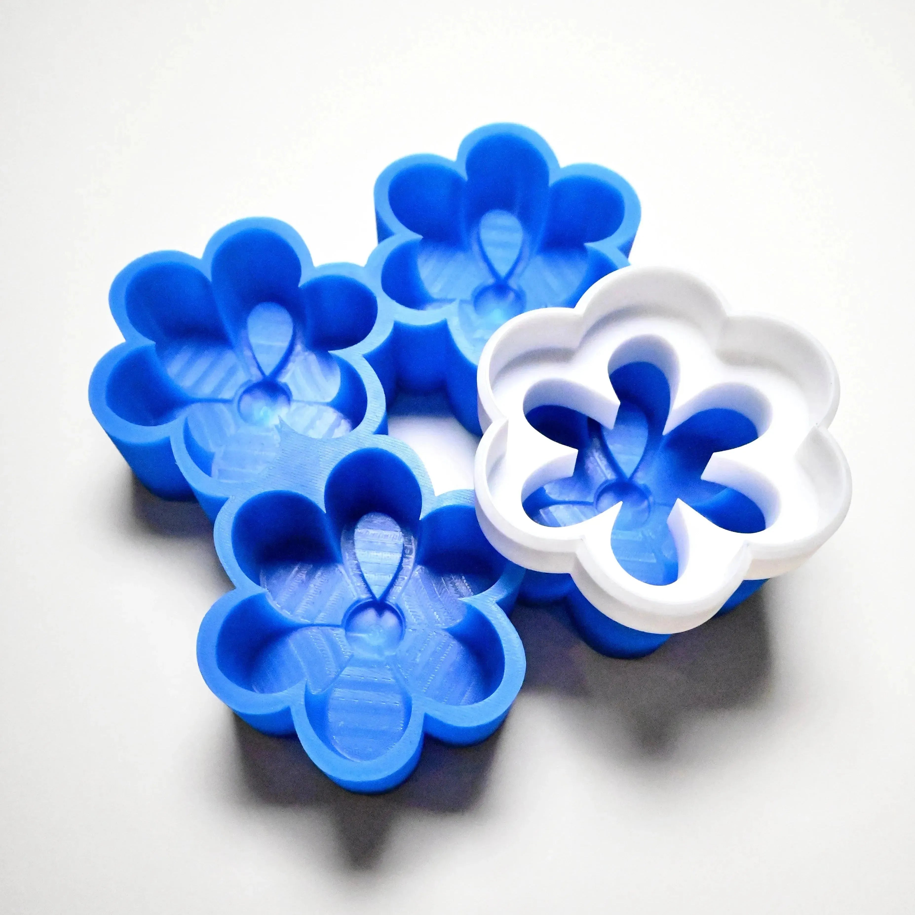 Blue silicone daisy molds with a white flower-shaped cutter on top.