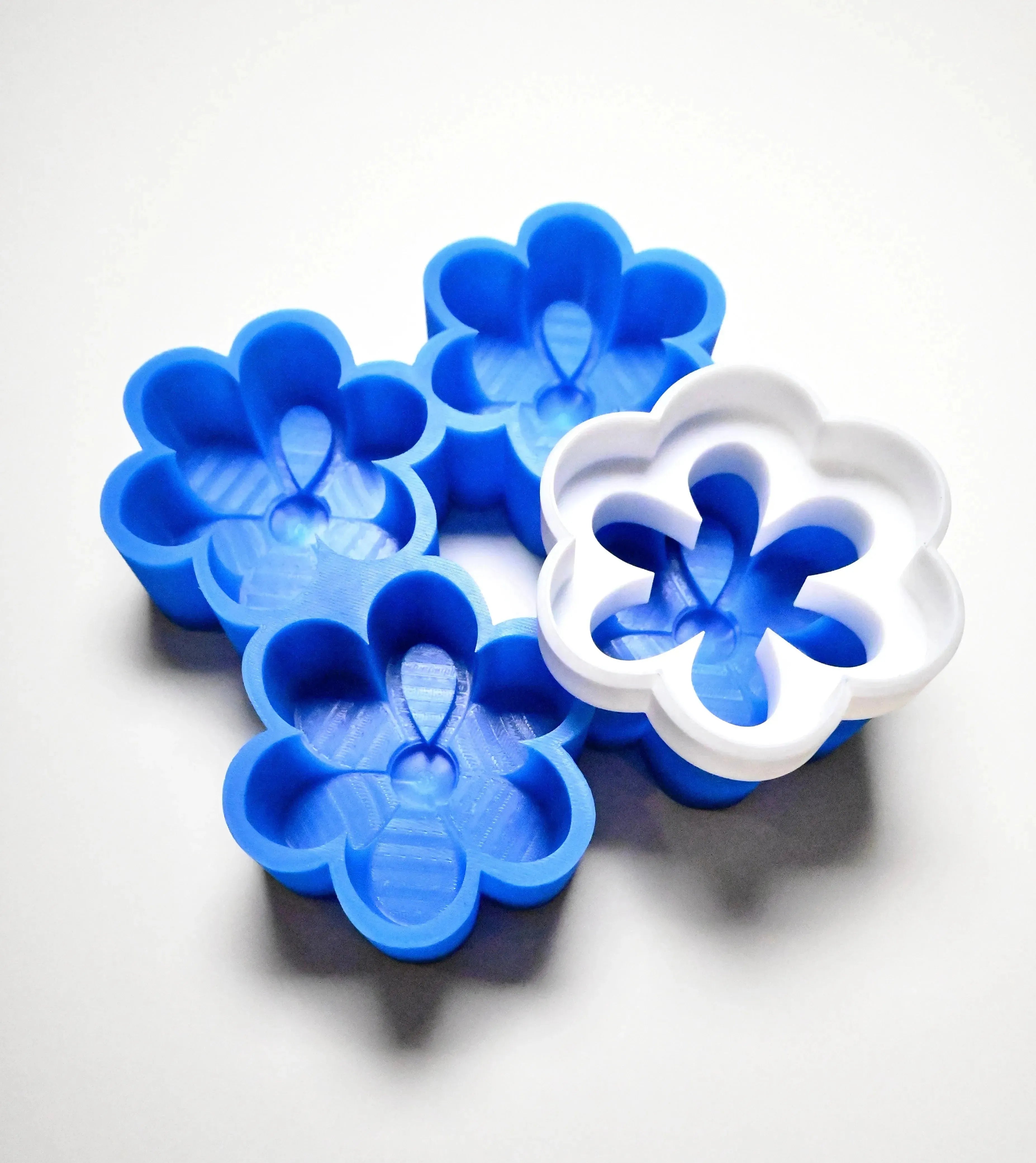 Blue silicone daisy molds with a white flower-shaped cutter on top.