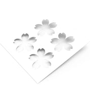 White plastic pastry stencil featuring four cherry blossom sakura flower cutouts.