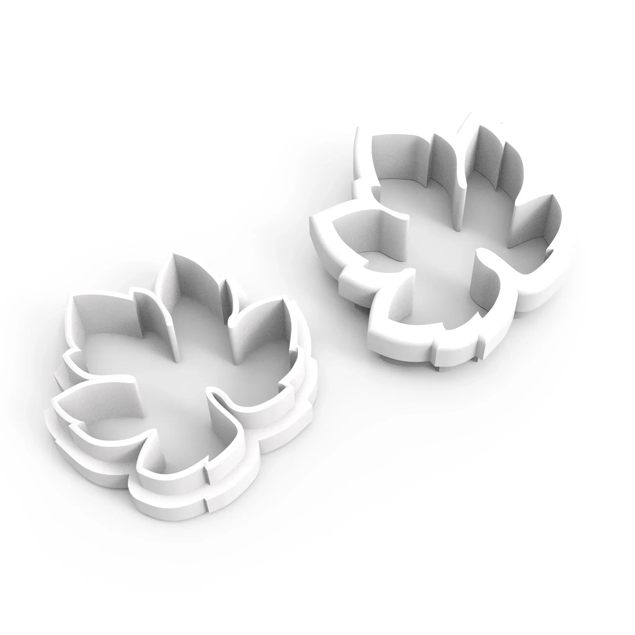 Two white, plastic vine leaf cookie cutters with detailed botanical shapes.