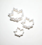 Three white plastic maple leaf cookie cutters in small, medium, and large sizes.