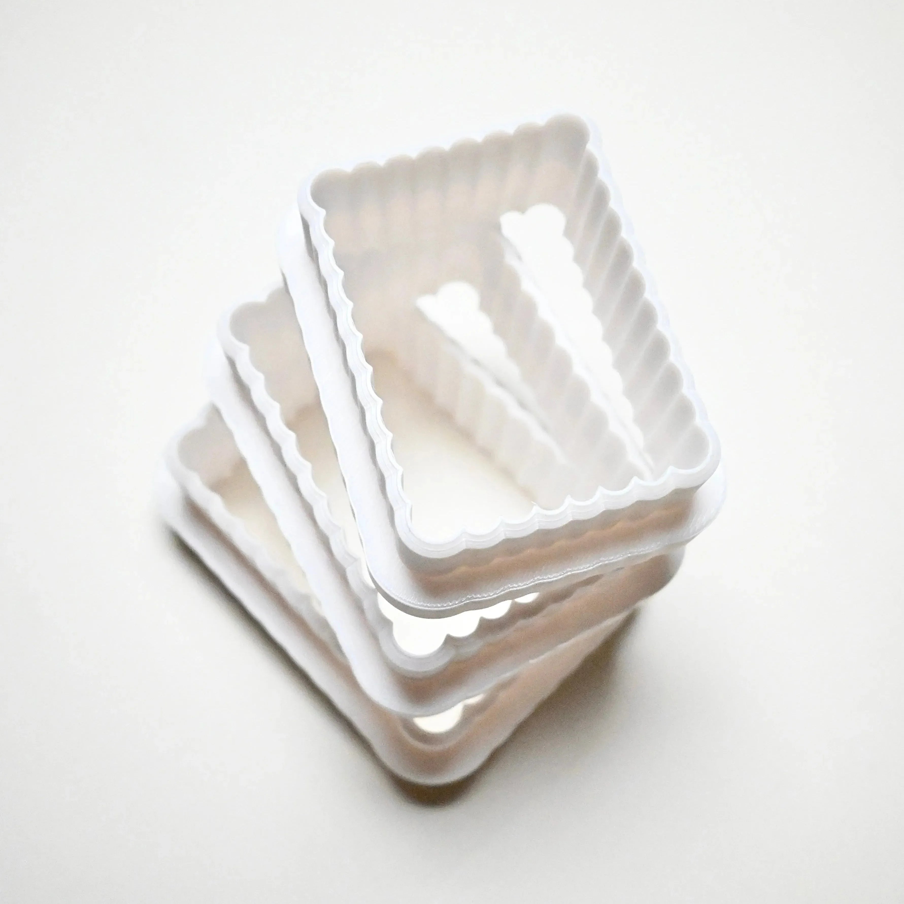 Stack of white plastic fluted rectangle cookie cutters in graduated sizes.