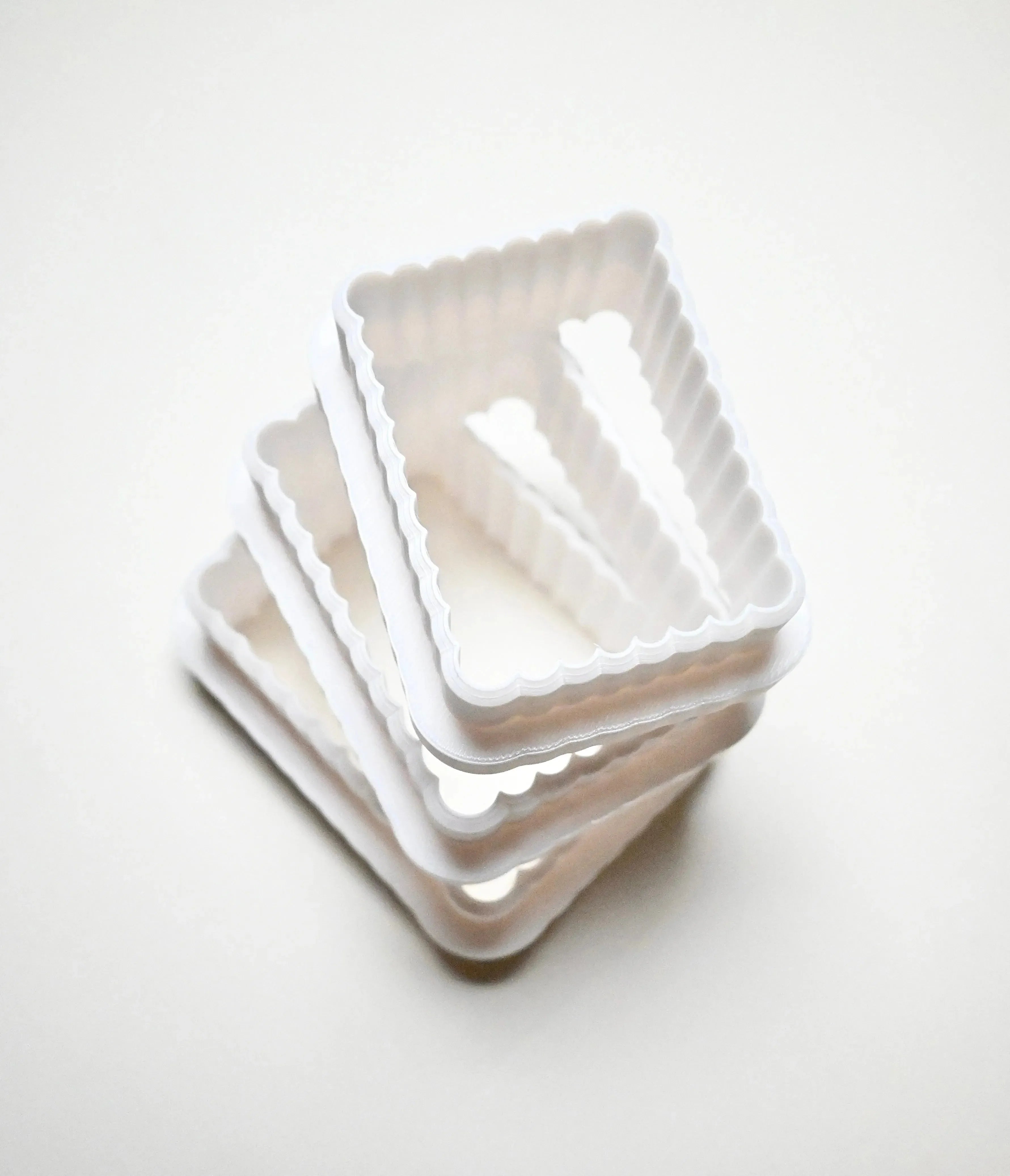 Stack of white plastic fluted rectangle cookie cutters in graduated sizes.