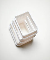 Stack of white plastic fluted rectangle cookie cutters in graduated sizes.