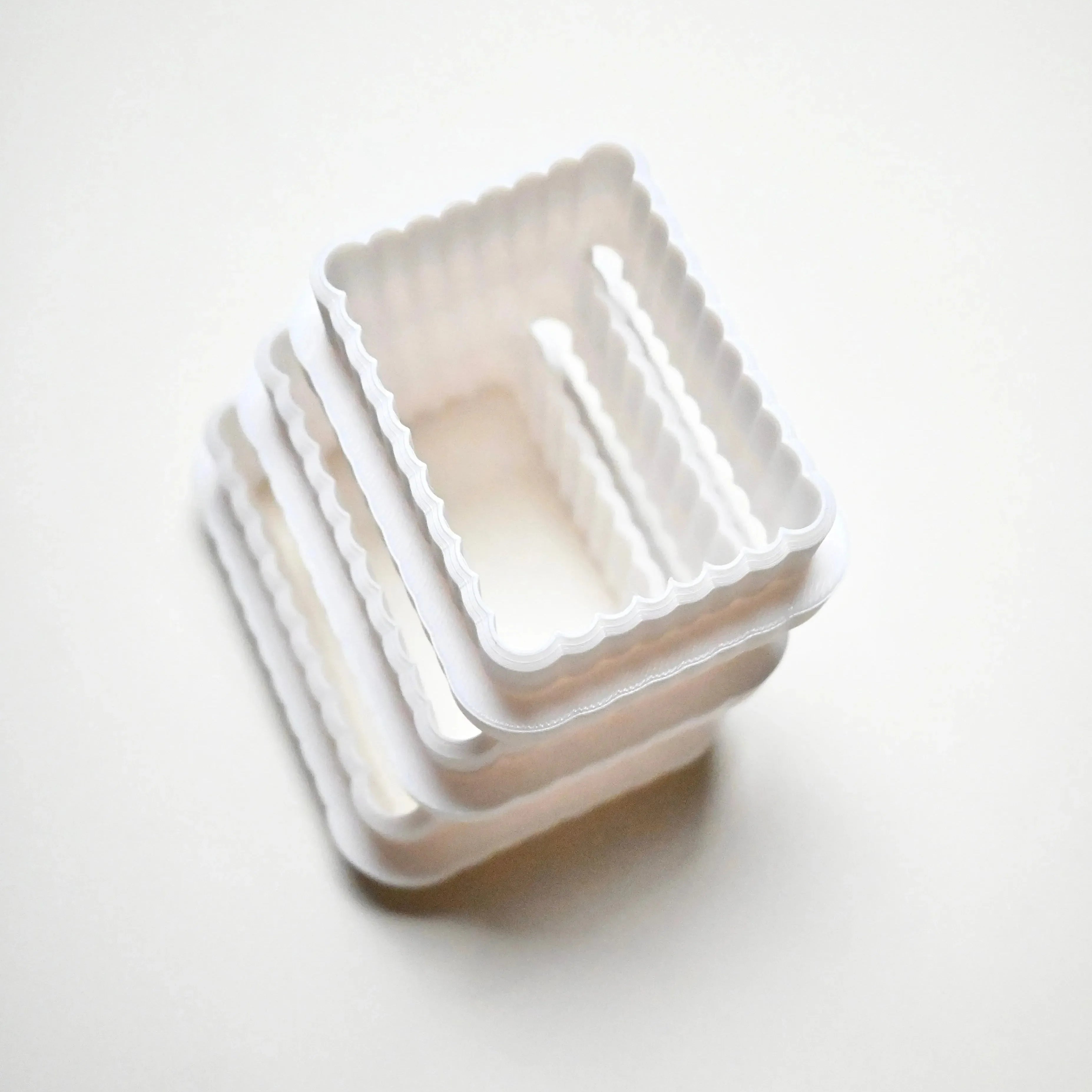Stack of white plastic fluted rectangle cookie cutters in graduated sizes.