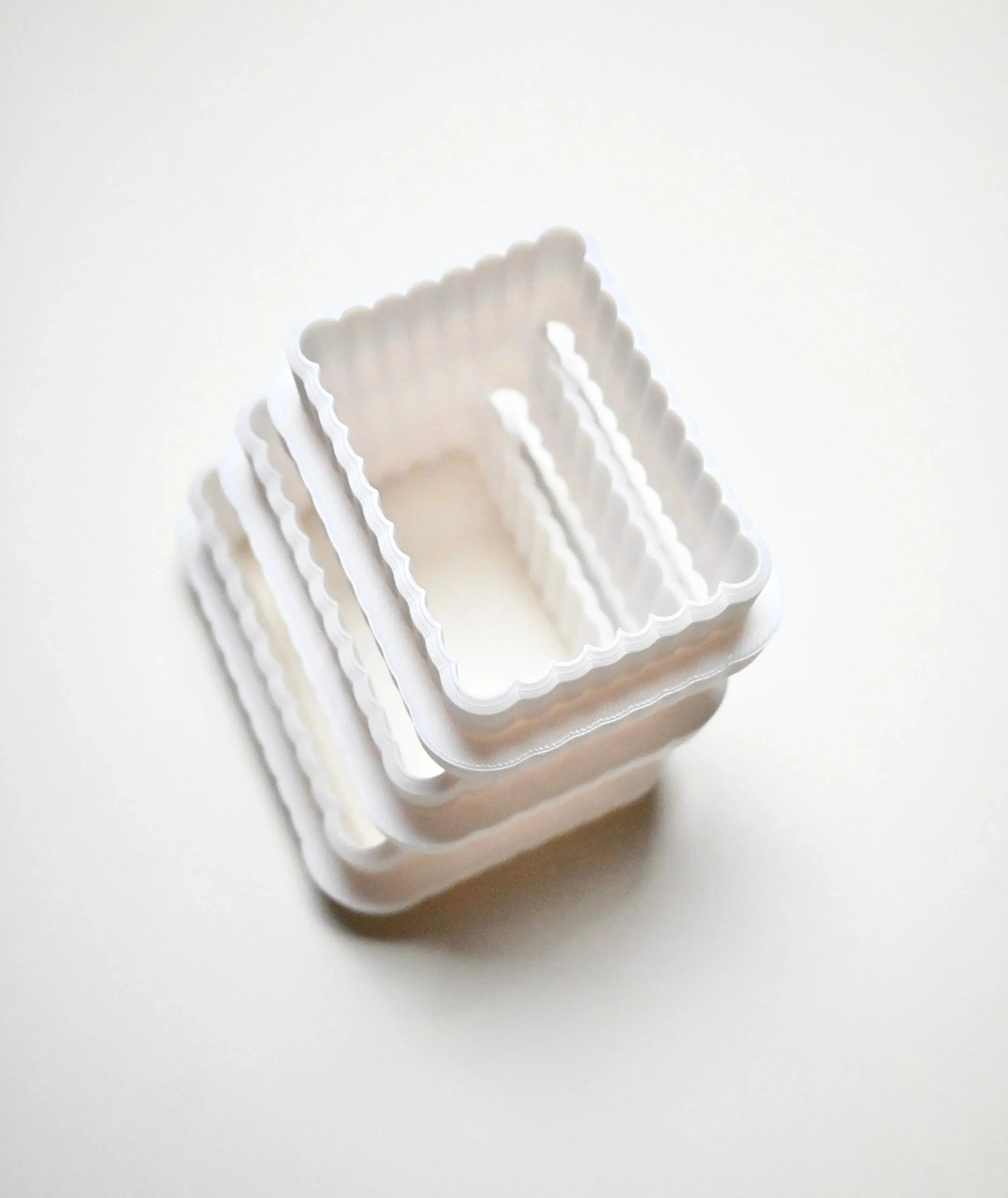 Stack of white plastic fluted rectangle cookie cutters in graduated sizes.