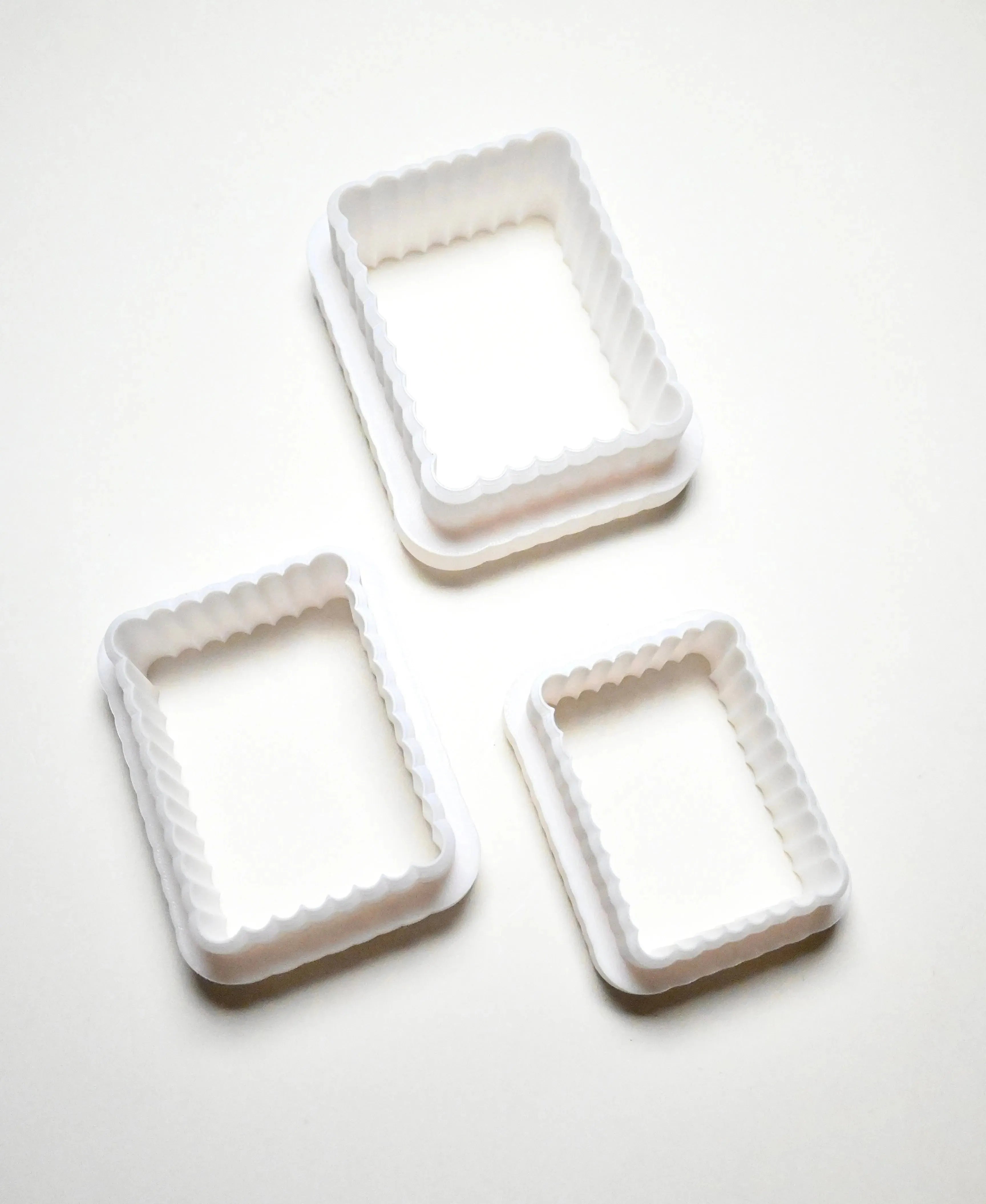 Three white plastic fluted rectangle cookie cutters in different sizes.