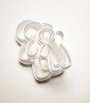 Three white plastic gingerbread man cookie cutters in different sizes stacked on a white background.