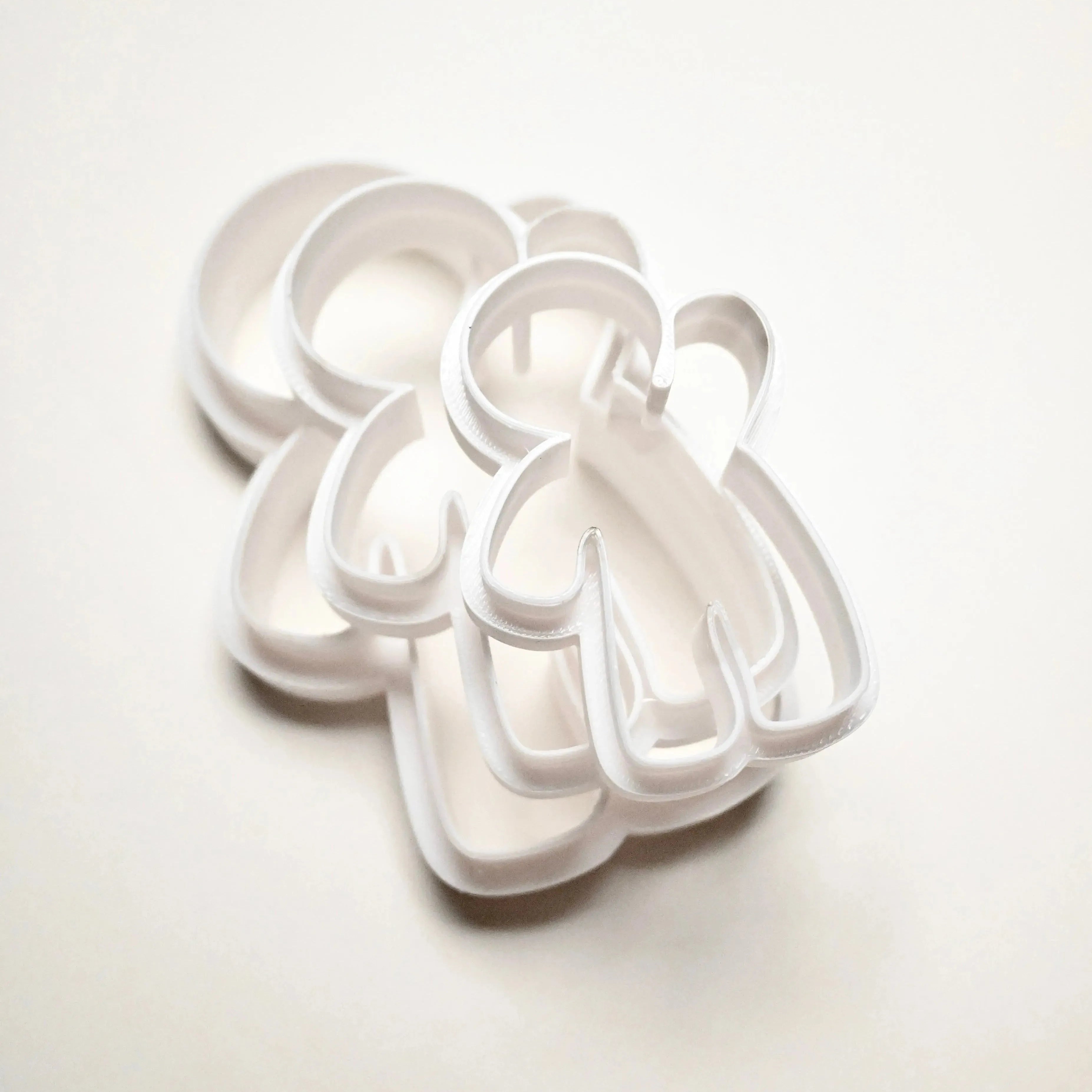 Three white plastic gingerbread man cookie cutters in different sizes stacked on a white background.