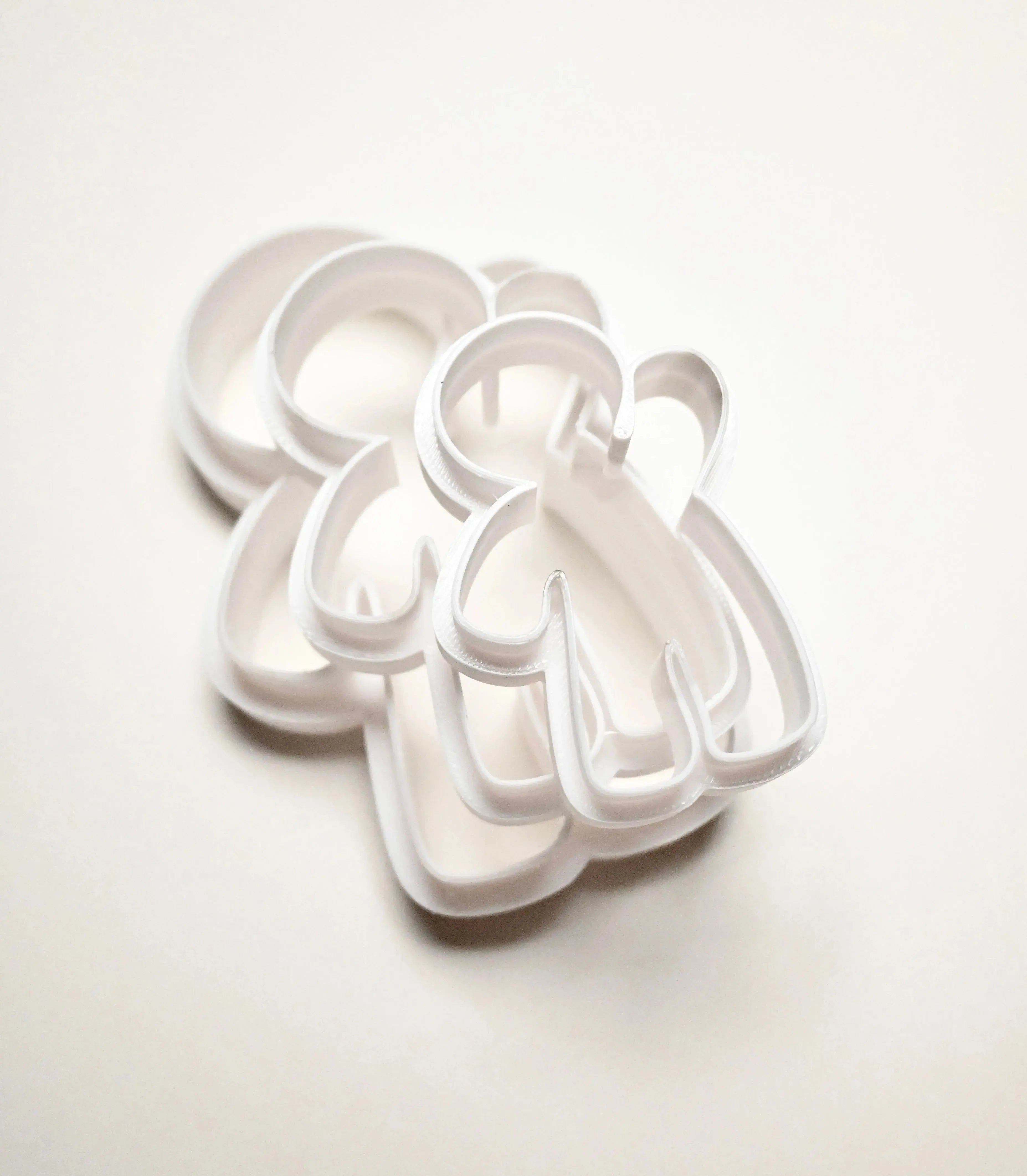 Three white plastic gingerbread man cookie cutters in different sizes stacked on a white background.