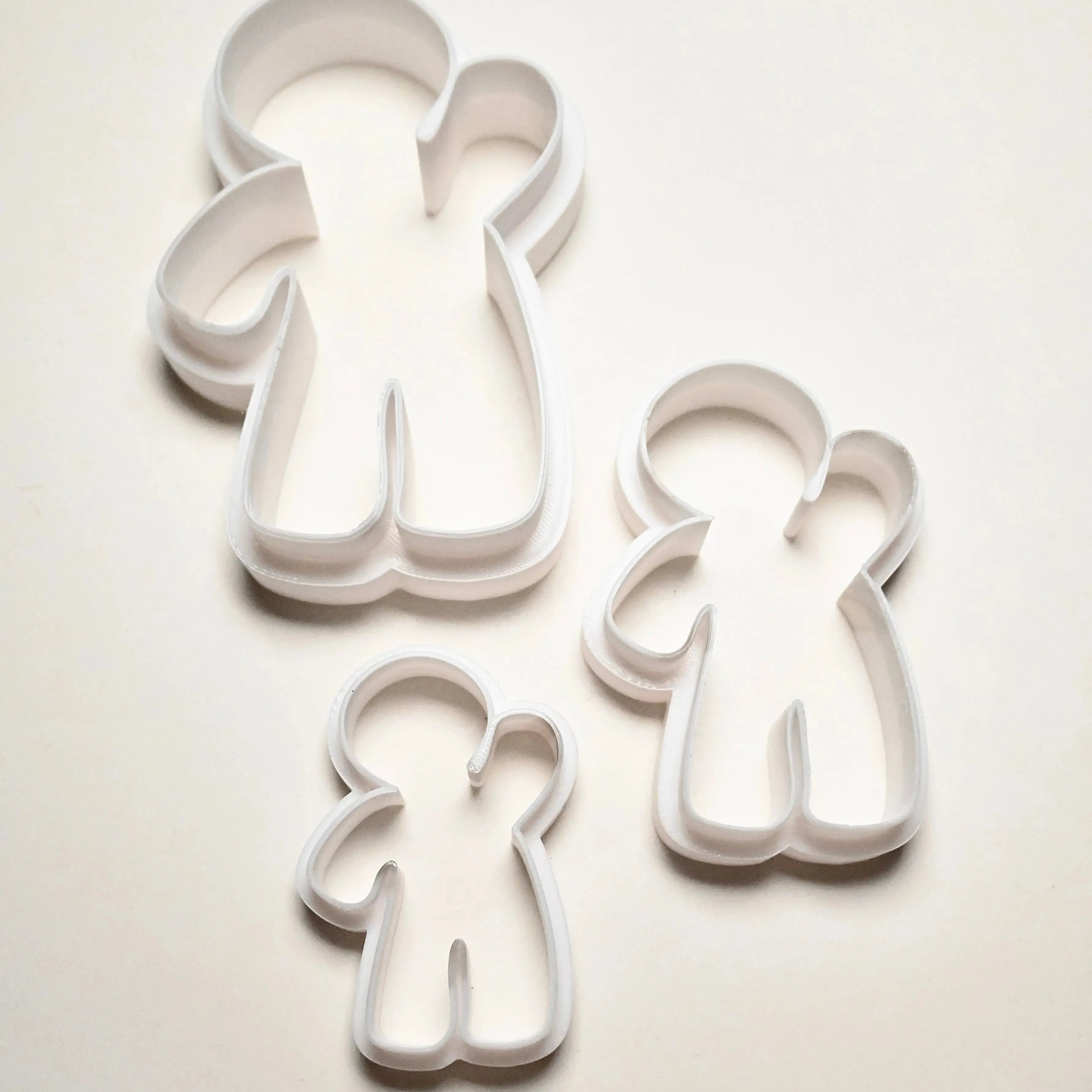 Three white plastic gingerbread man cookie cutters in small, medium, and large sizes.