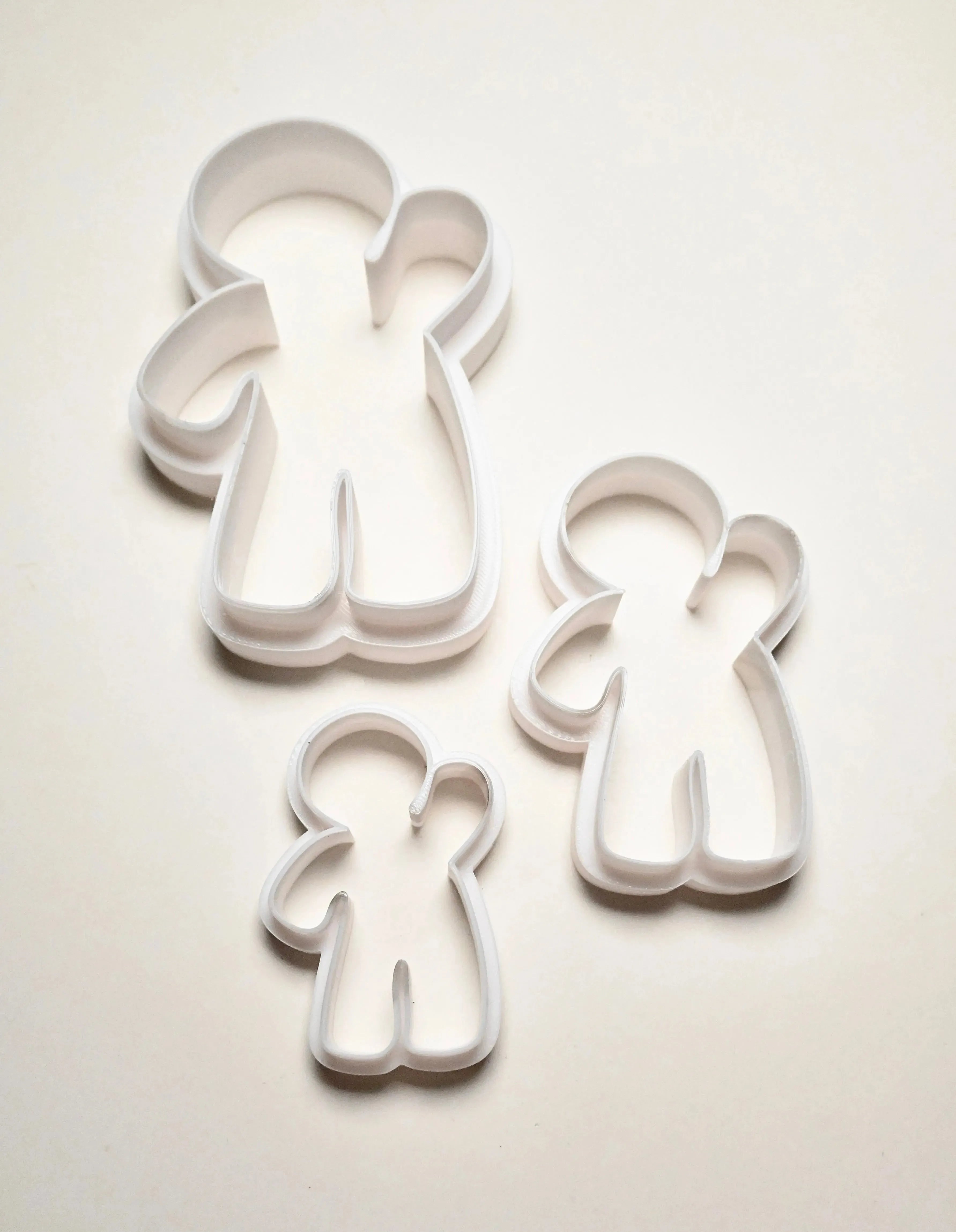 Three white plastic gingerbread man cookie cutters in small, medium, and large sizes.