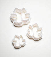 Three white plastic vine leaf cookie cutters in small, medium, and large sizes.