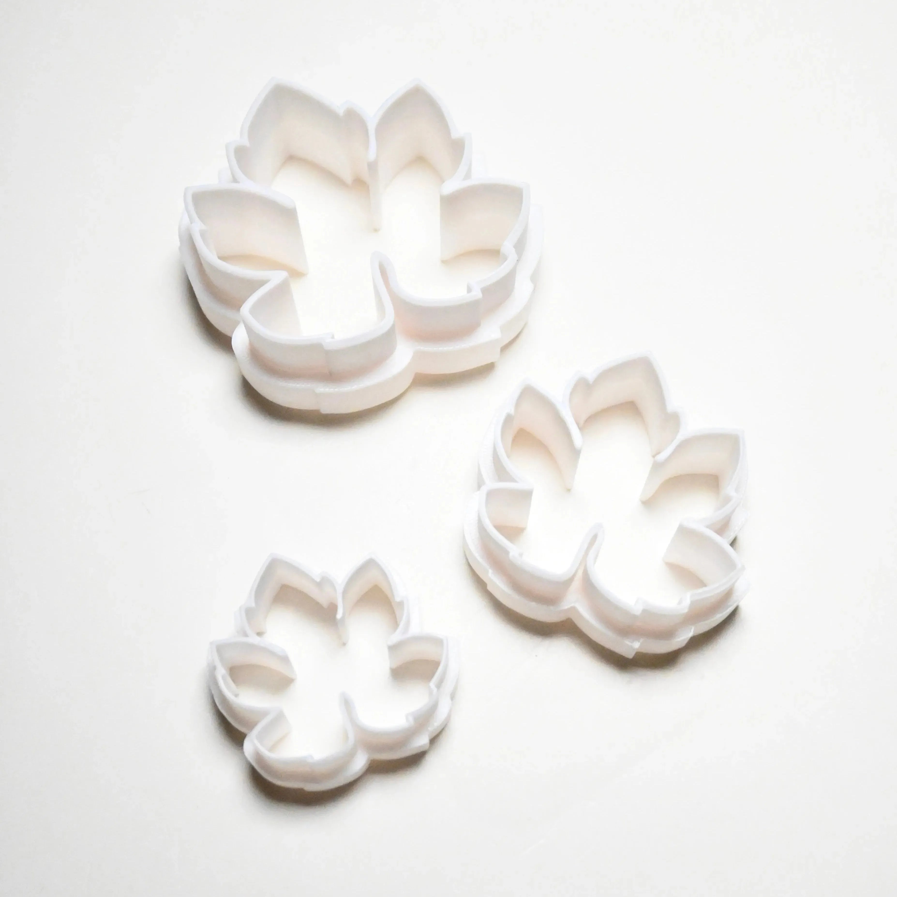 Three white plastic vine leaf cookie cutters in small, medium, and large sizes.