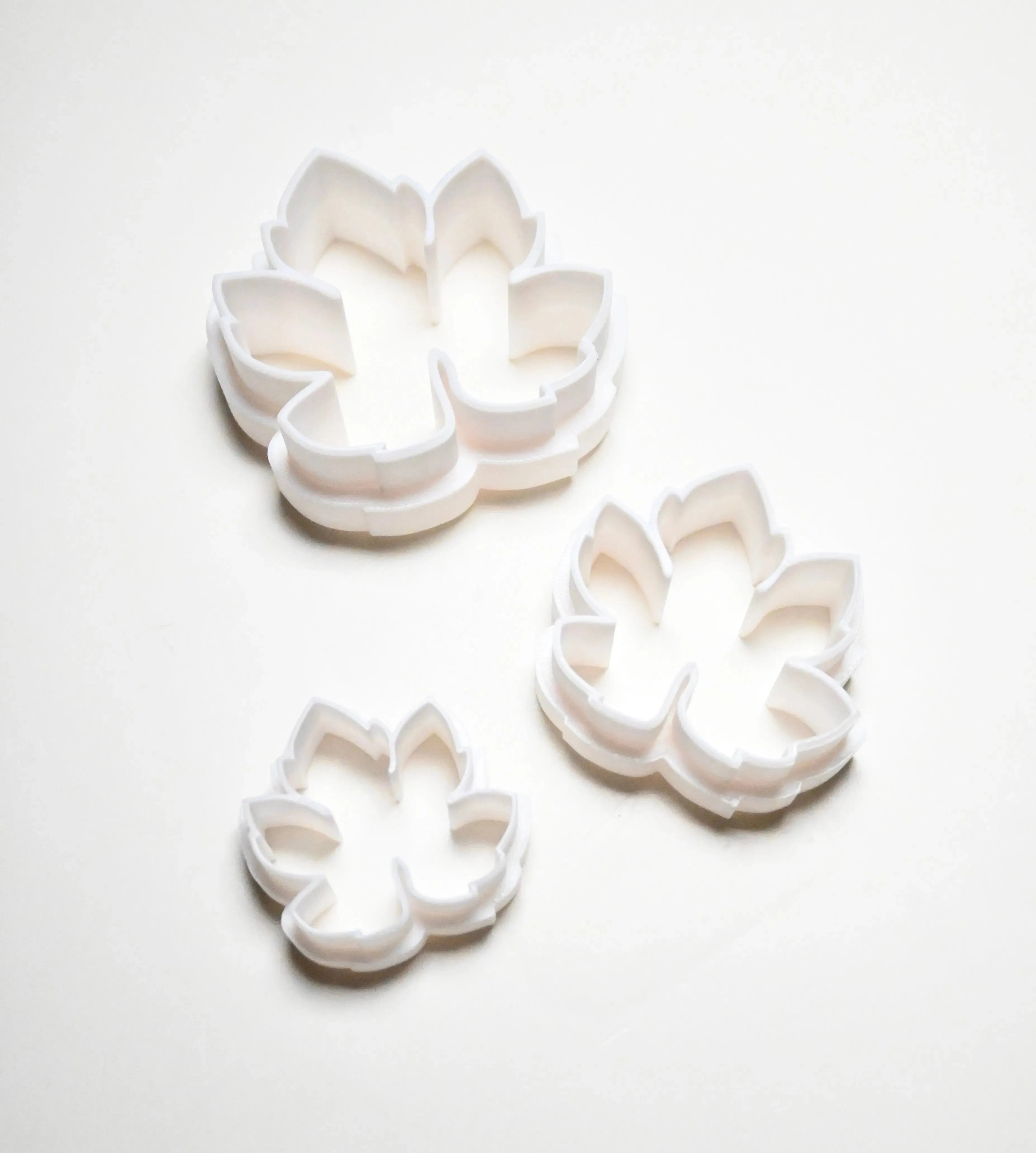 Three white plastic vine leaf cookie cutters in small, medium, and large sizes.