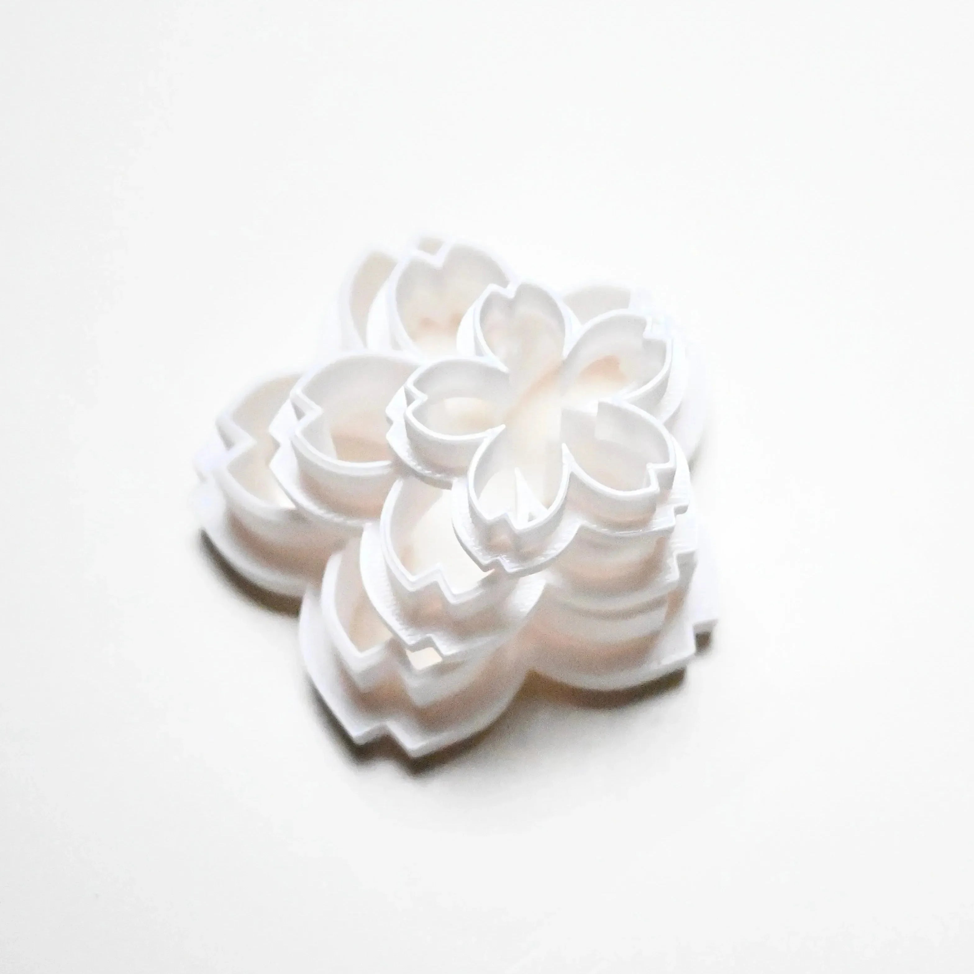 Stacked white plastic sakura flower cookie cutters in various sizes.