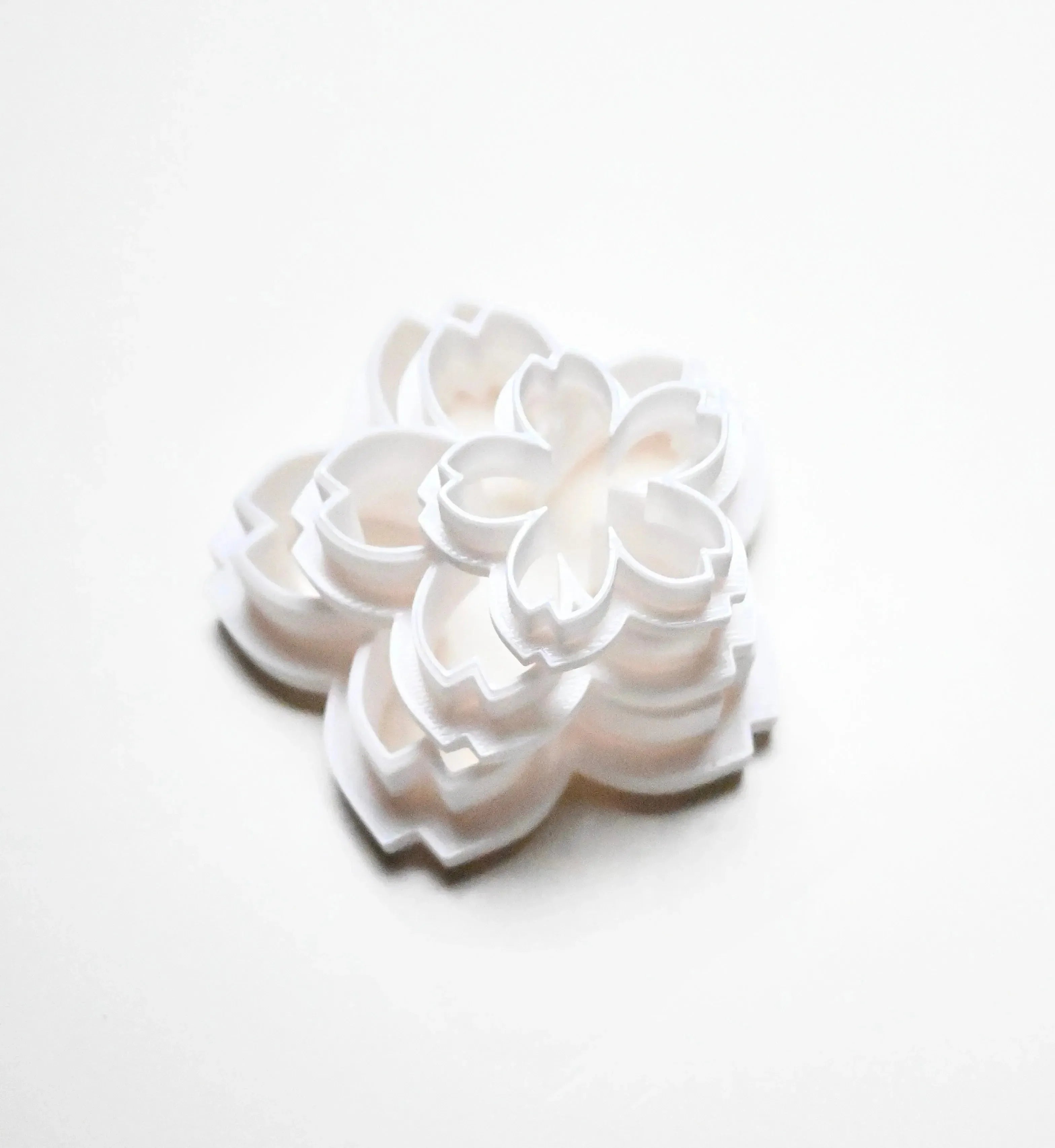 Stacked white plastic sakura flower cookie cutters in various sizes.