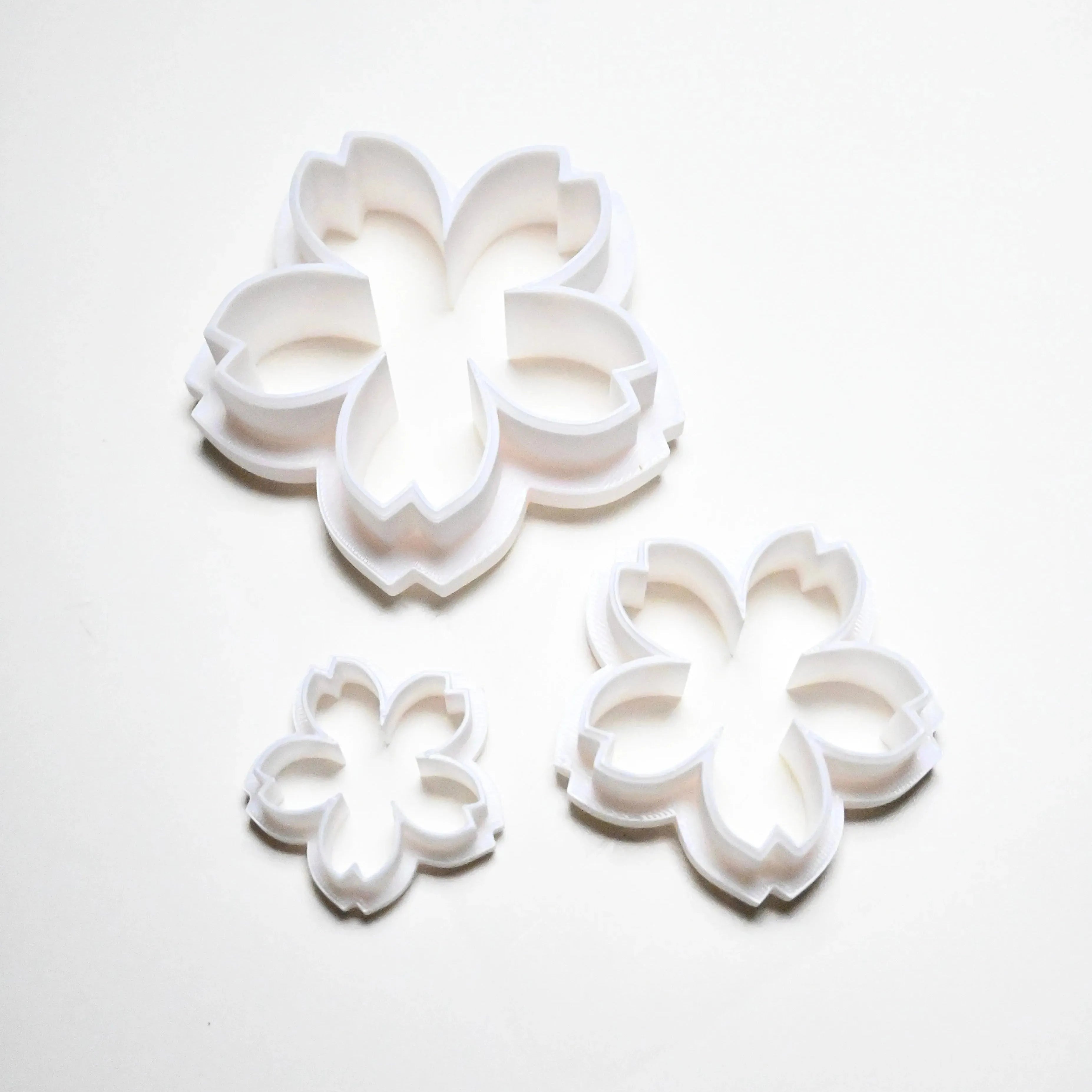 Three white plastic sakura cherry blossom cookie cutters in small, medium, and large sizes.
