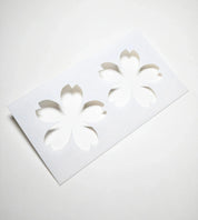 White plastic Sakura pastry stencil with two cherry blossom flower cutouts.