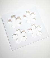 White square pastry stencil with four cherry blossom sakura cutouts.