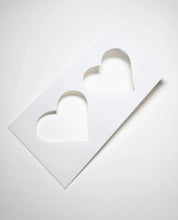 White rectangular plastic pastry stencil featuring two cut-out heart shapes.