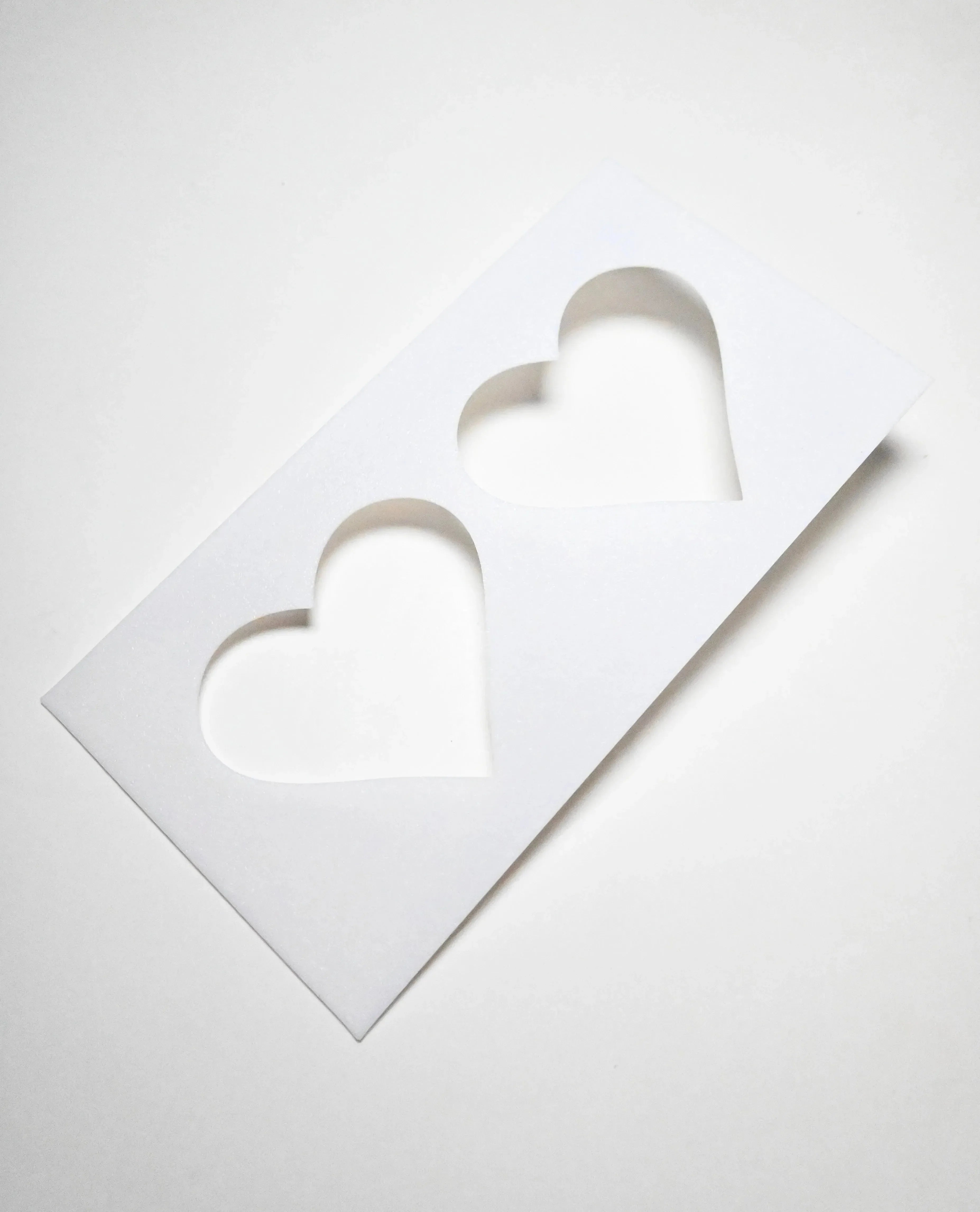 White rectangular plastic pastry stencil featuring two cut-out heart shapes.