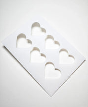 White plastic TBmolds pastry stencil with six heart-shaped cutouts.