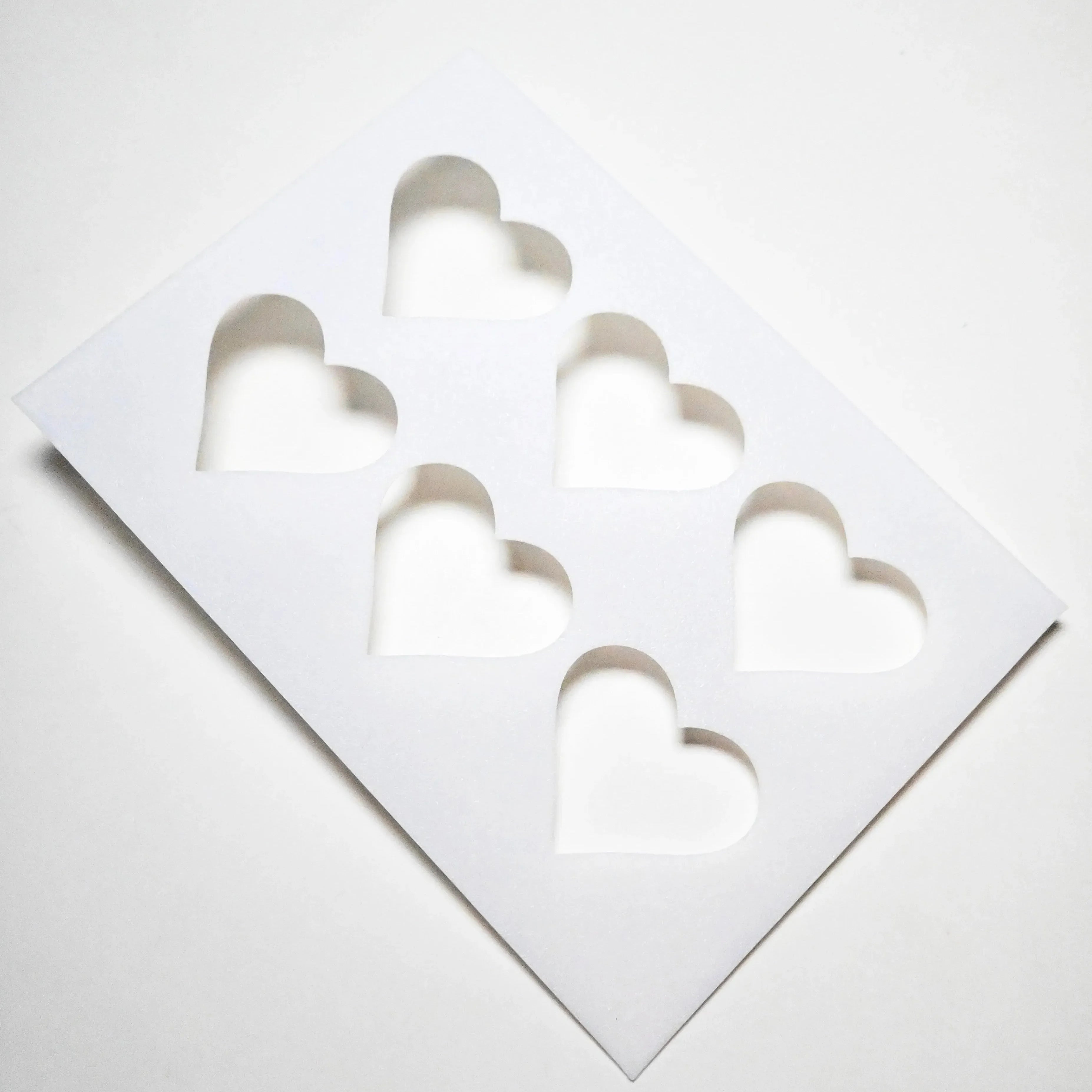 White plastic TBmolds pastry stencil with six heart-shaped cutouts.