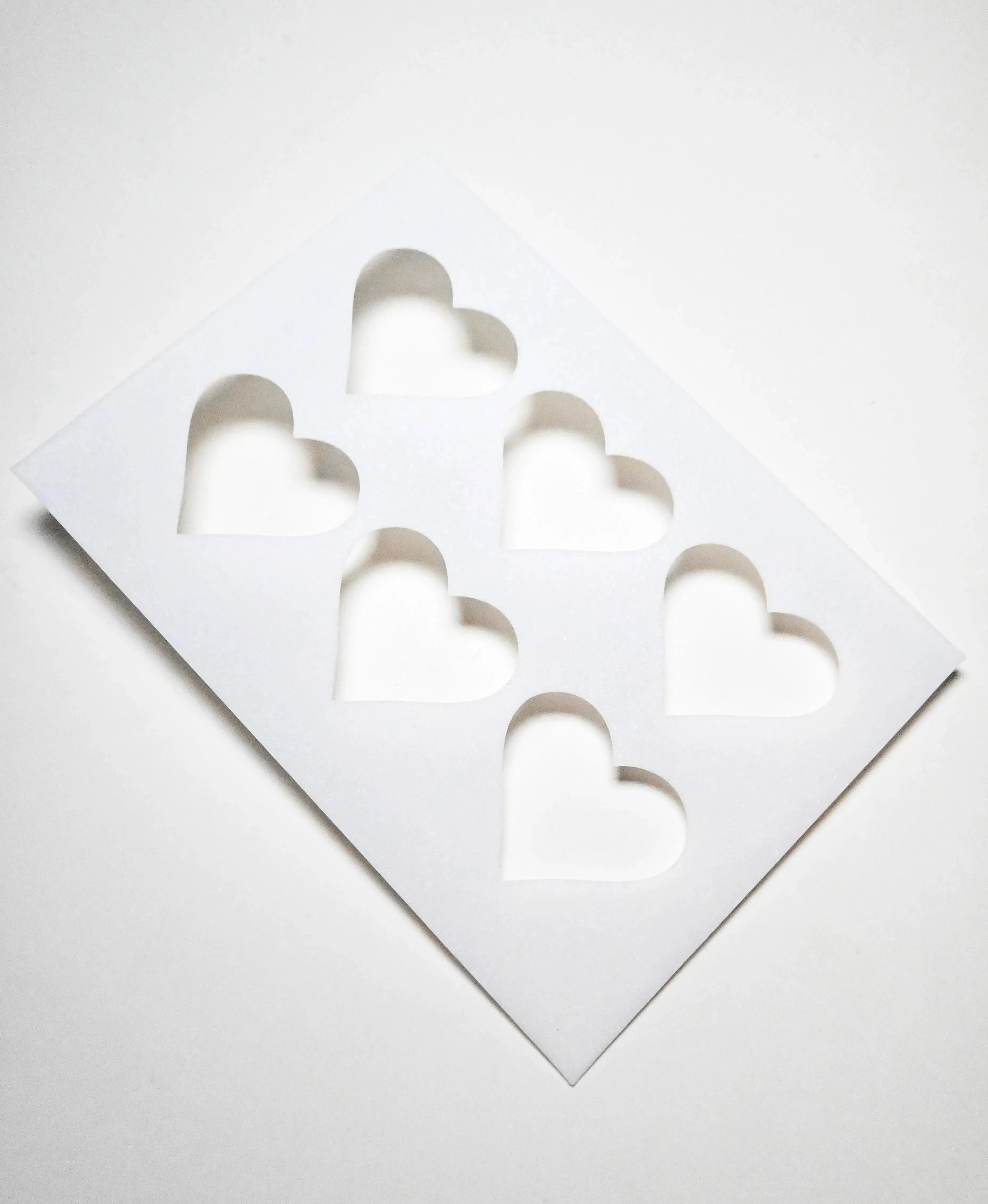 White plastic TBmolds pastry stencil with six heart-shaped cutouts.