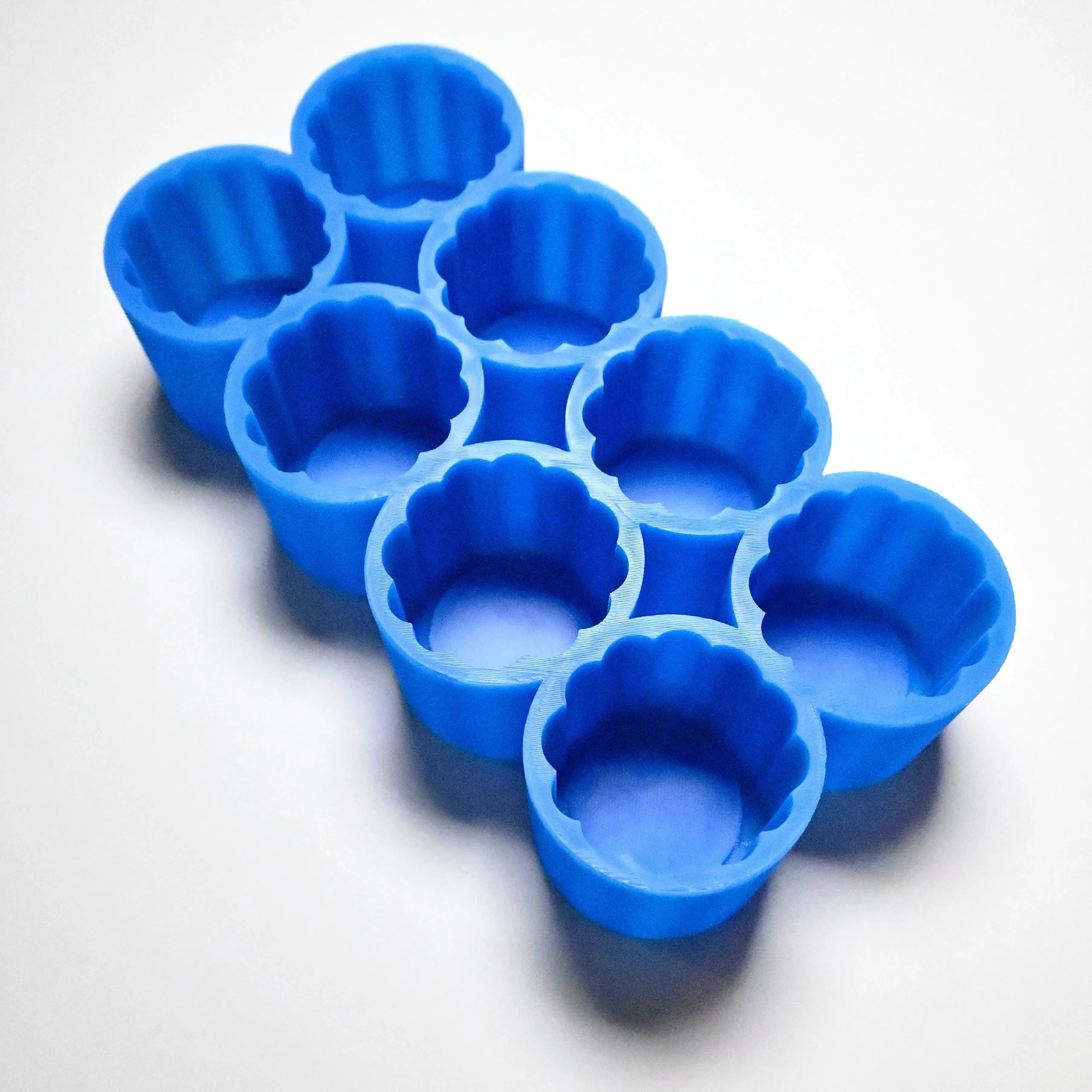 Blue silicone Mini Charlotte mold with eight fluted, flower-shaped cavities.