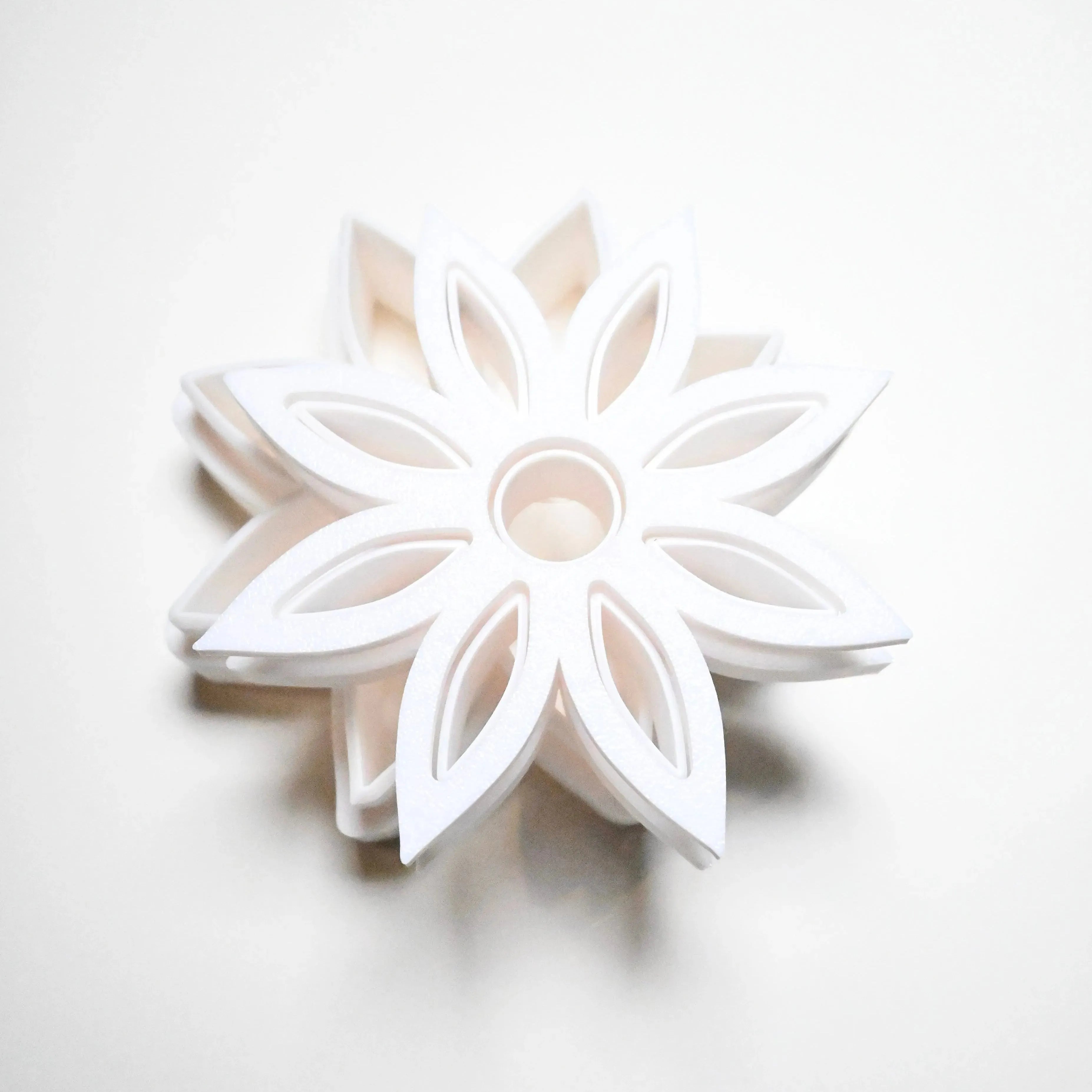 White plastic star anise flower cookie cutter with a detailed eight-petal geometric design.