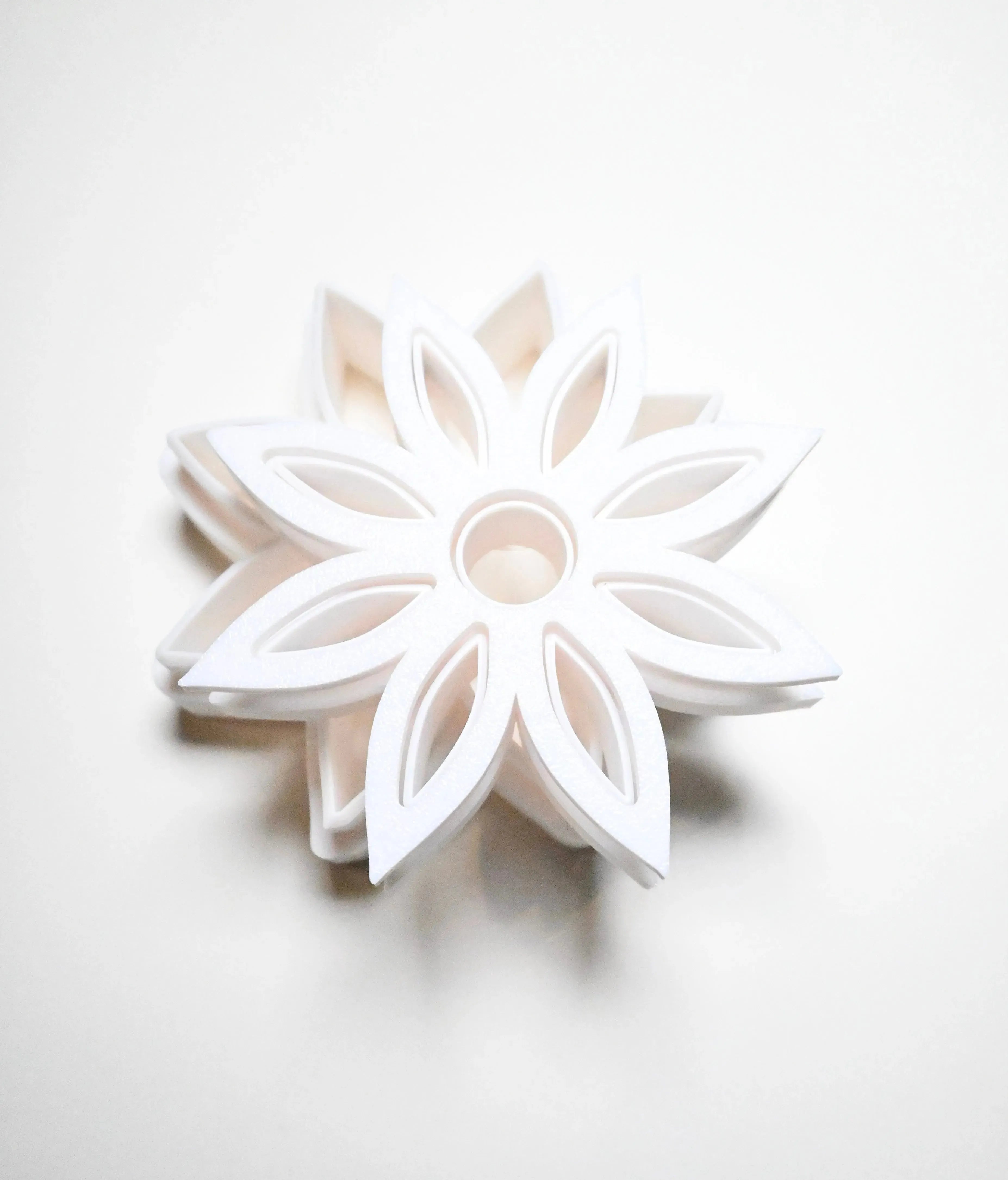 White plastic star anise flower cookie cutter with a detailed eight-petal geometric design.