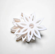 White plastic star anise flower cookie cutter with sharp, pointed petals.