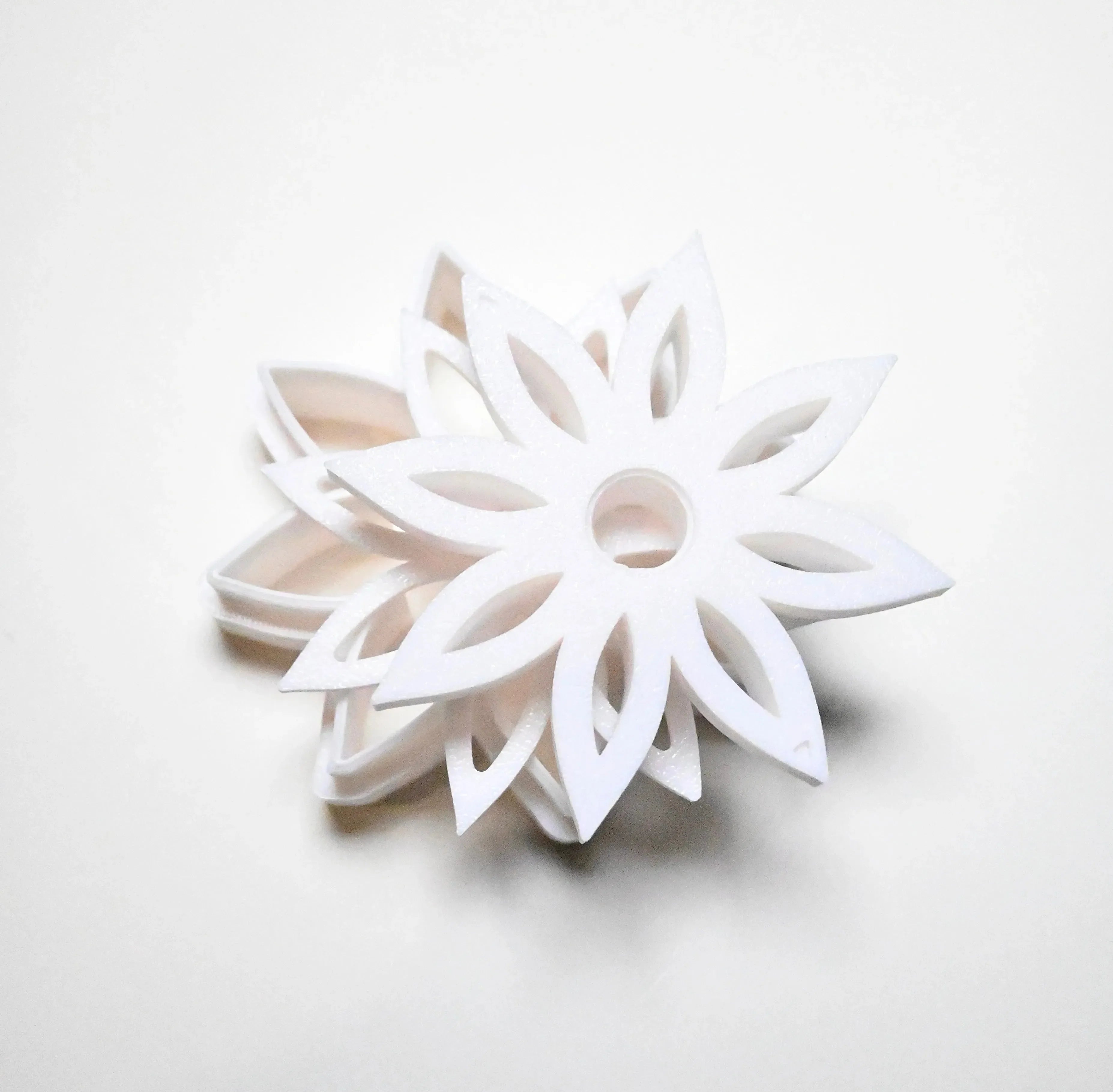 White plastic star anise flower cookie cutter with sharp, pointed petals.