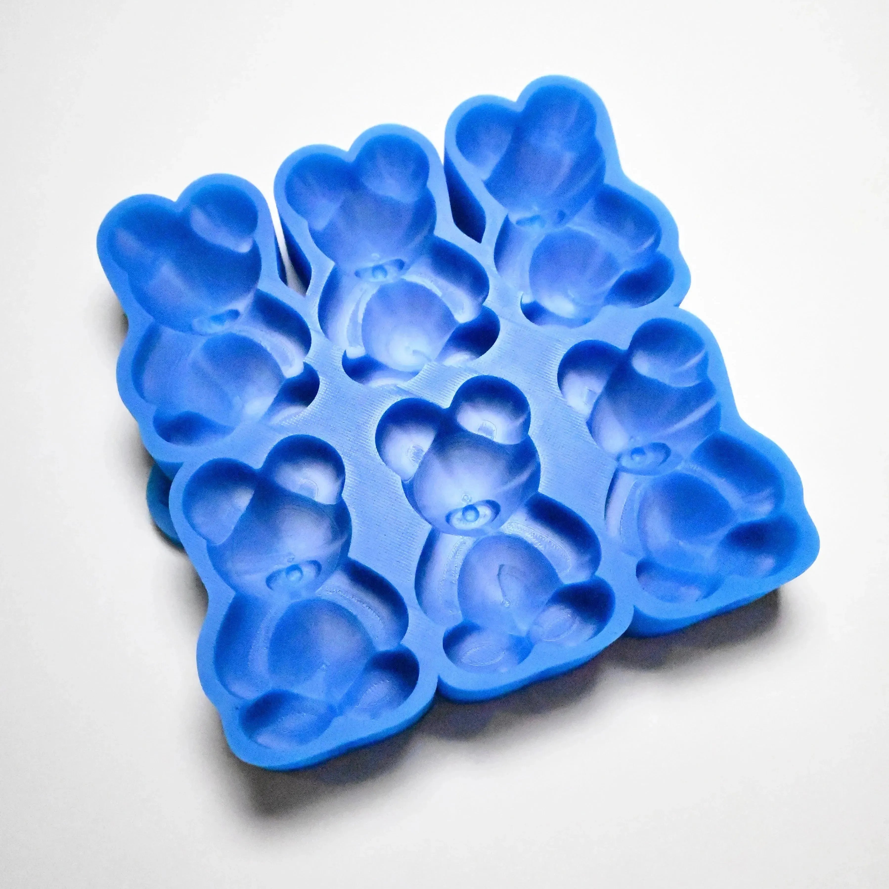 Blue silicone baking mold with six detailed teddy bear-shaped cavities.