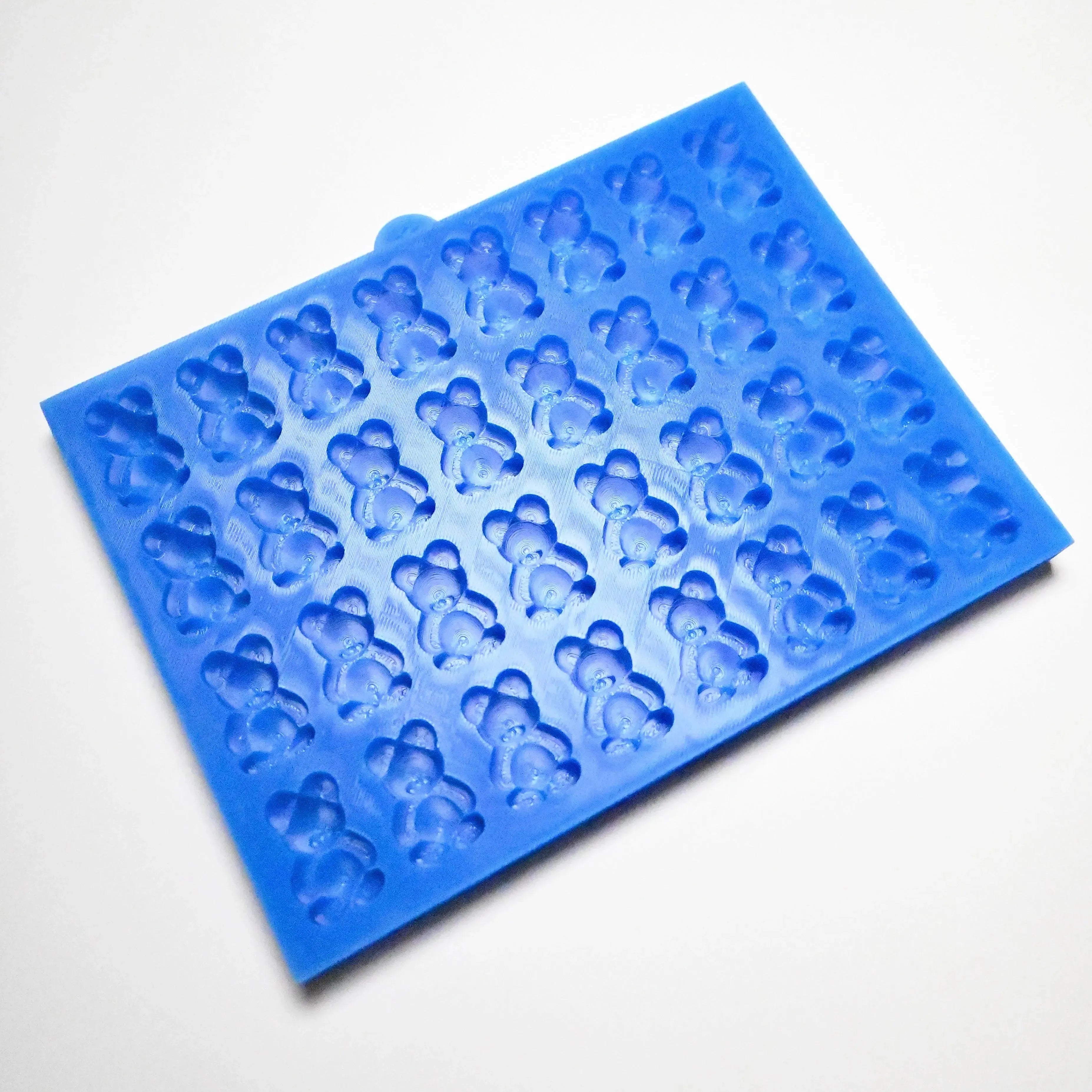 Blue silicone baking mold with multiple detailed mini bear-shaped cavities.