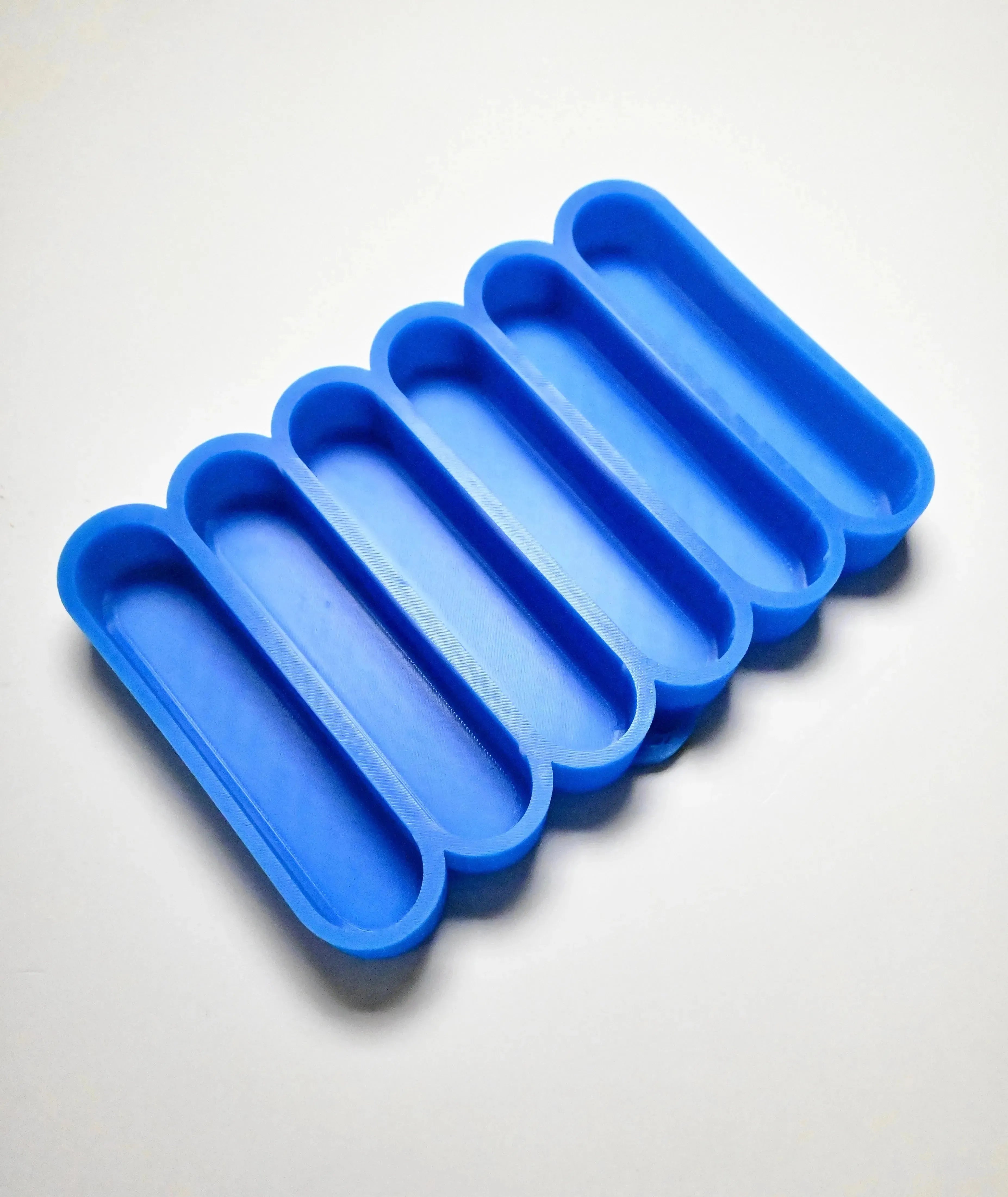 Blue silicone mold with six long, rounded finger-shaped cavities for pastry making.