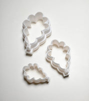 Three white plastic oak leaf cookie cutters in small, medium, and large sizes.