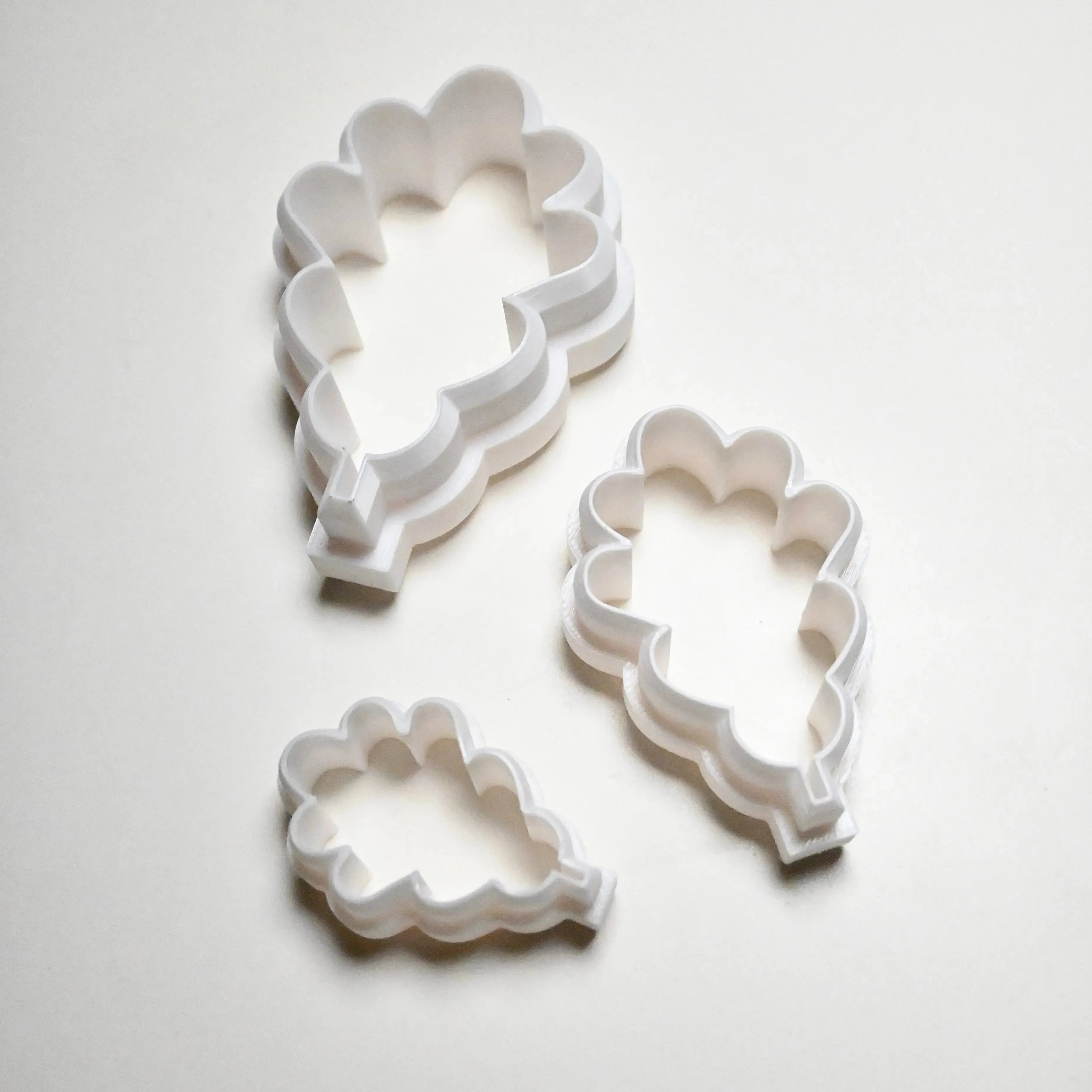 Three white plastic oak leaf cookie cutters in small, medium, and large sizes.