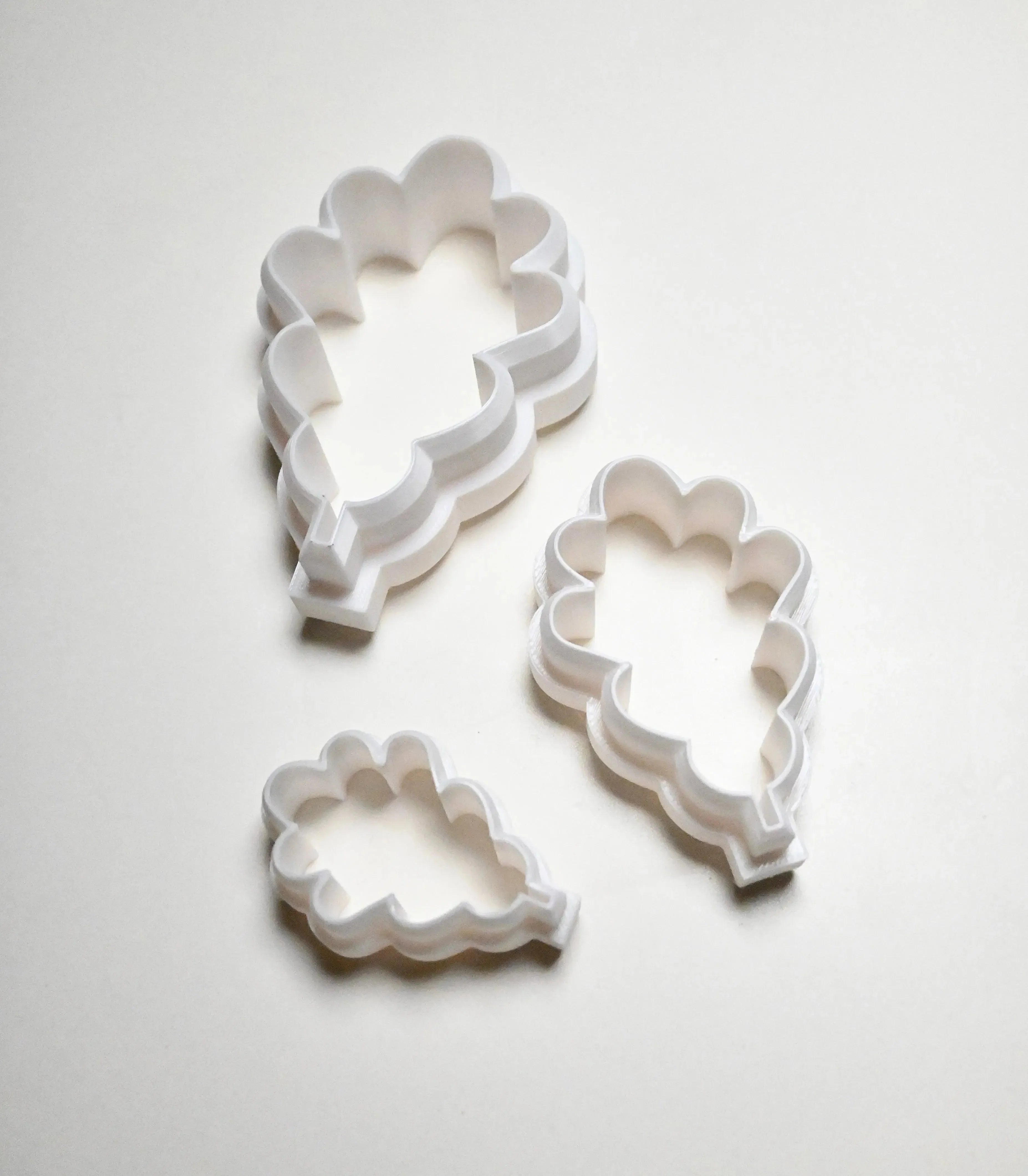 Three white plastic oak leaf cookie cutters in small, medium, and large sizes.