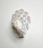 Stack of white plastic oak leaf cookie cutters in various sizes.