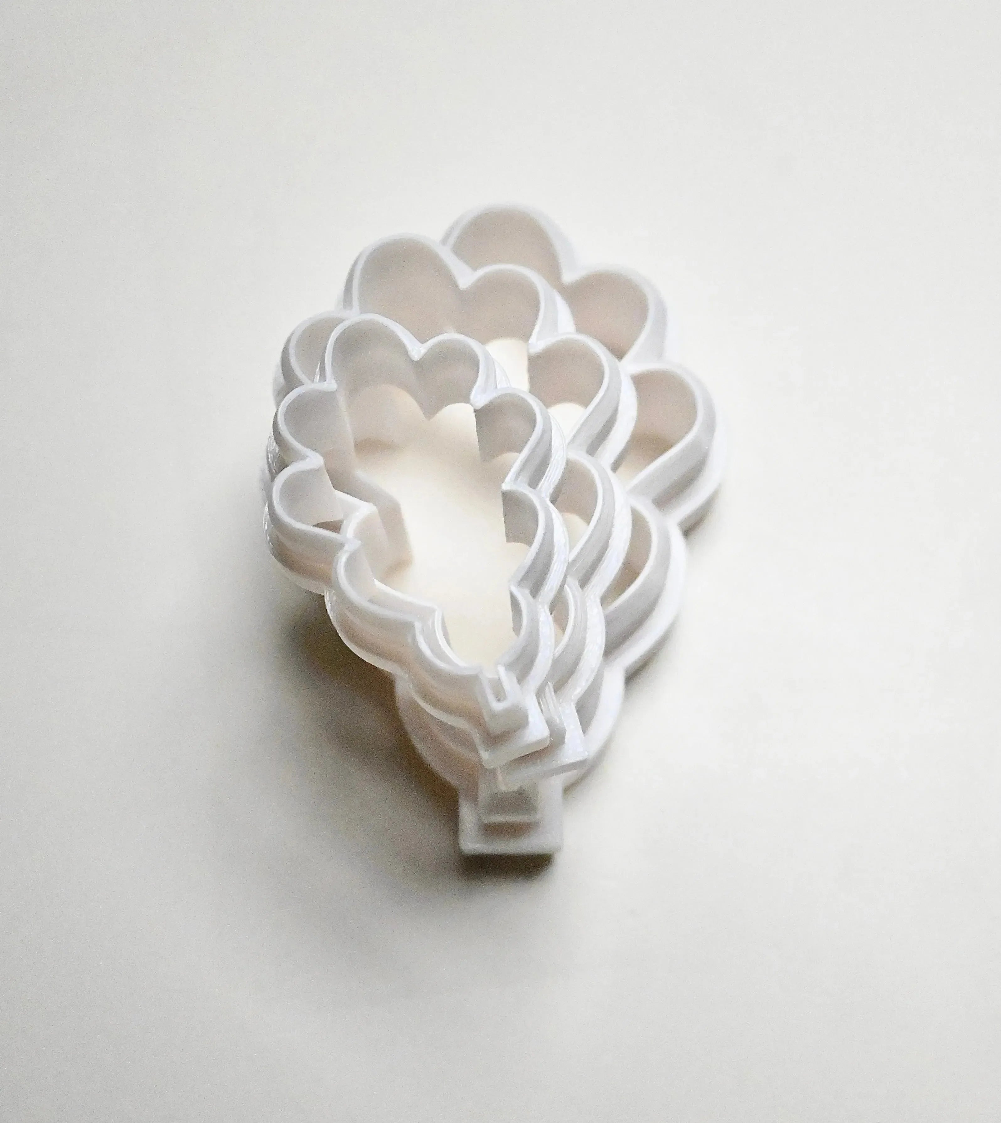 Stack of white plastic oak leaf cookie cutters in various sizes.