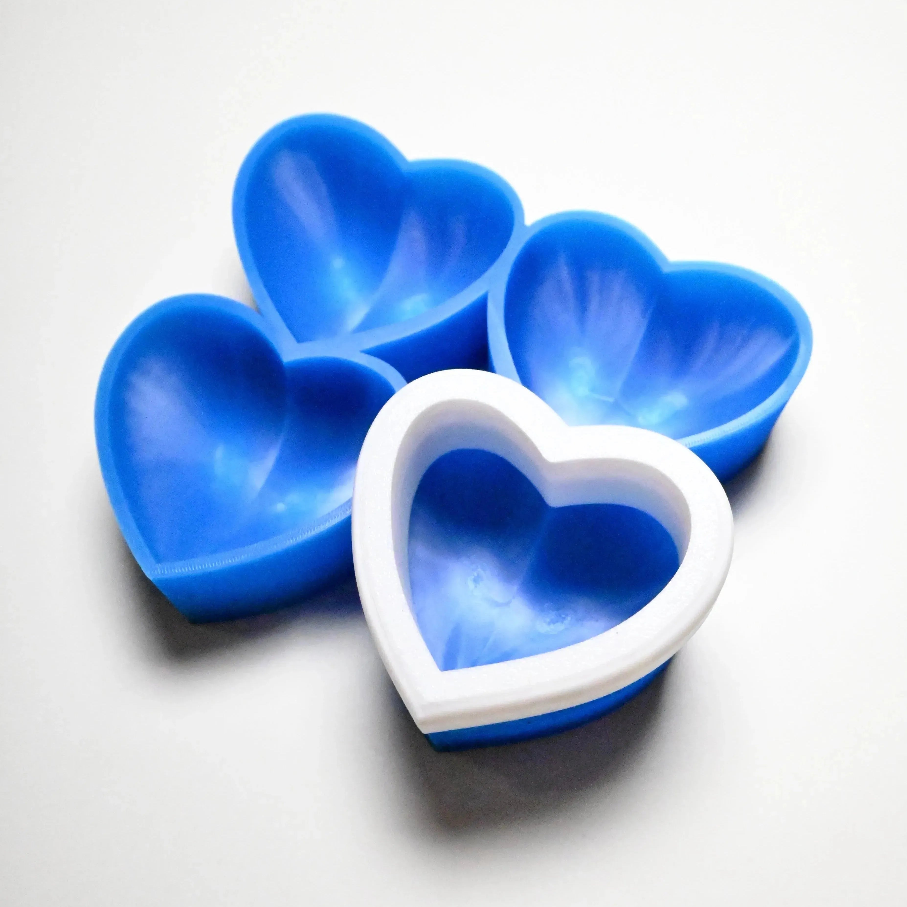 Blue silicone heart-shaped pastry molds with a white plastic support rim.