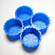 Four blue silicone fluted flower molds with detailed petal patterns inside.
