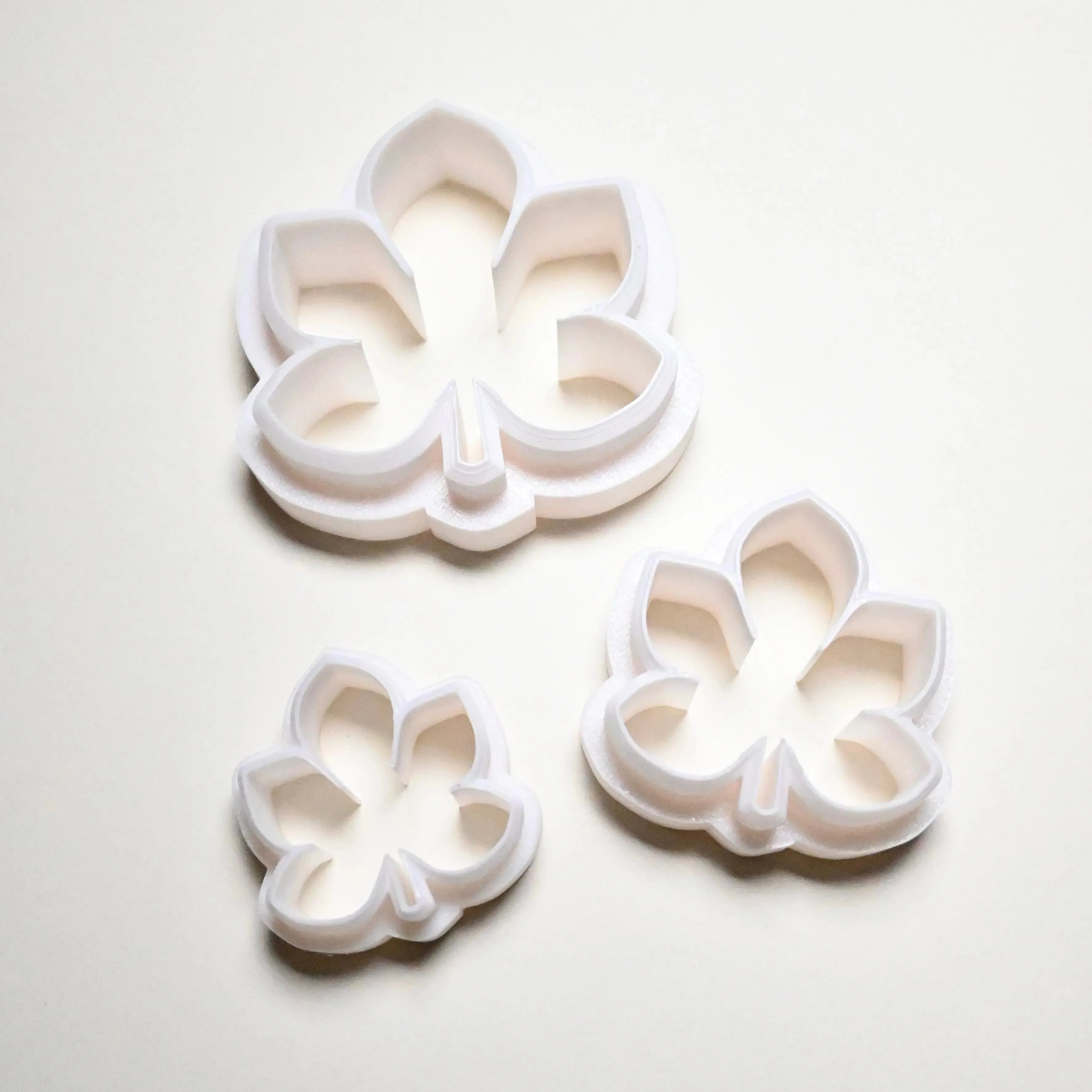 Three white plastic horse chestnut leaf cookie cutters in small, medium, and large sizes.