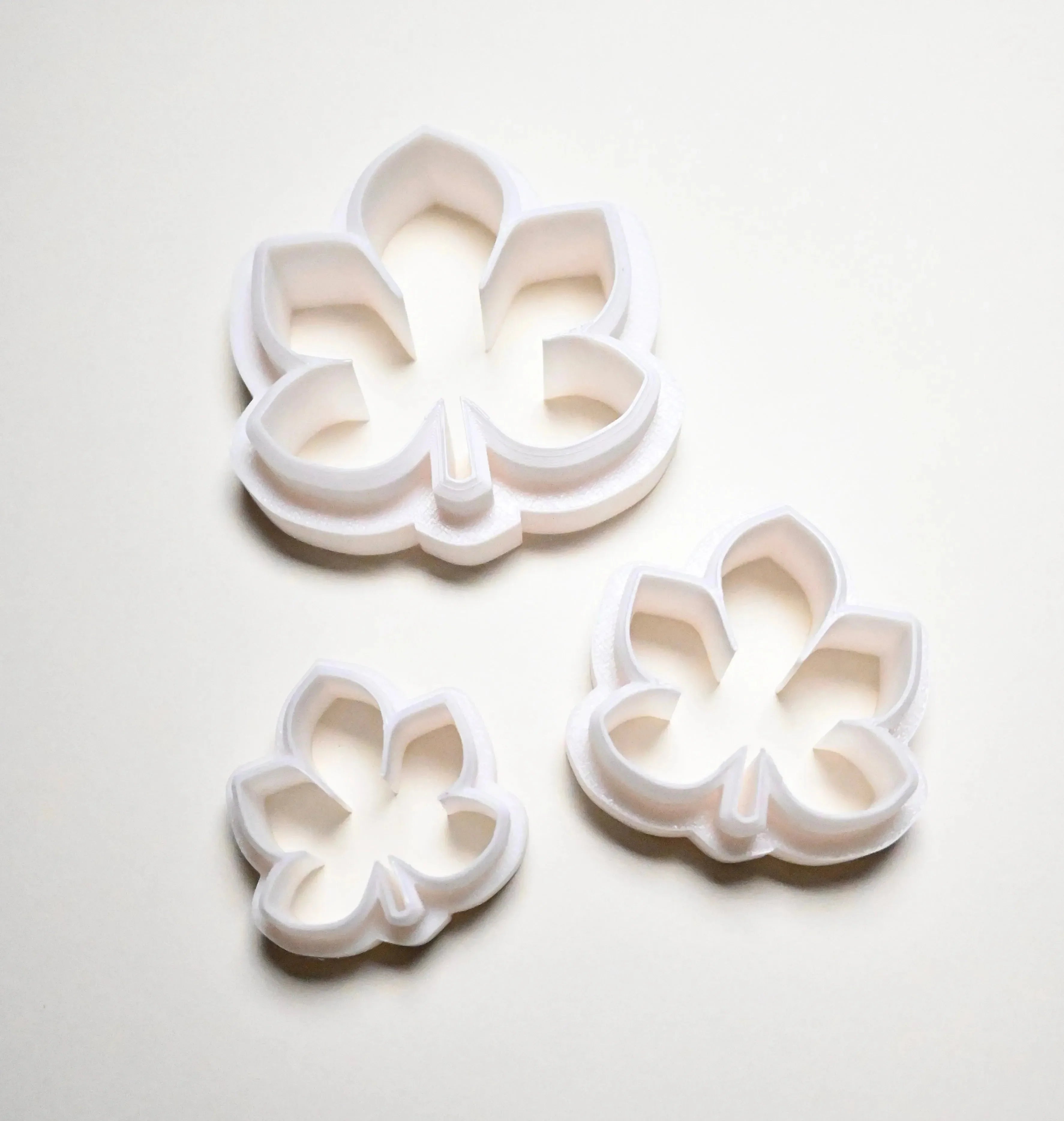 Three white plastic horse chestnut leaf cookie cutters in small, medium, and large sizes.