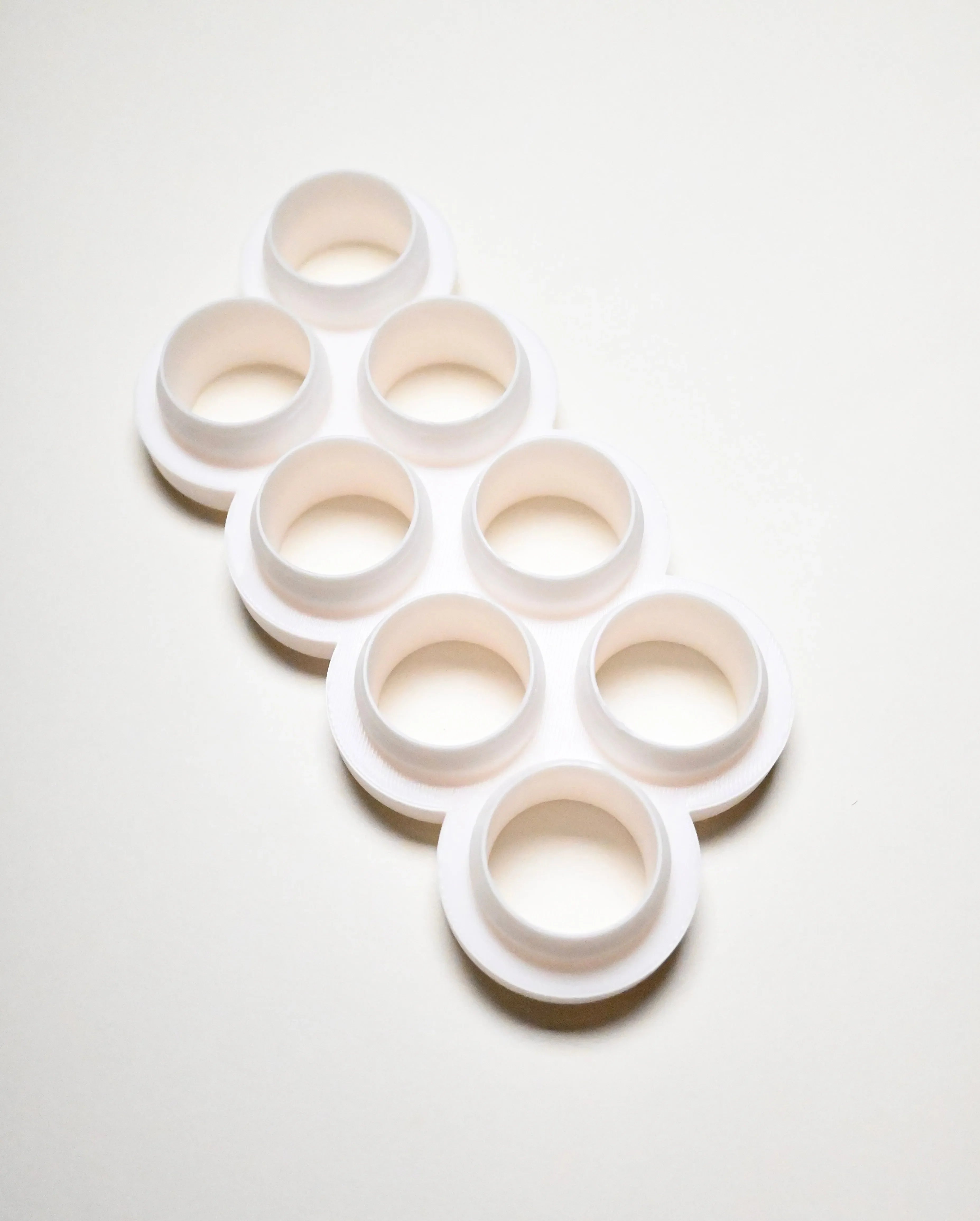 White multi-cookie cutter with eight circular molds in a staggered layout.